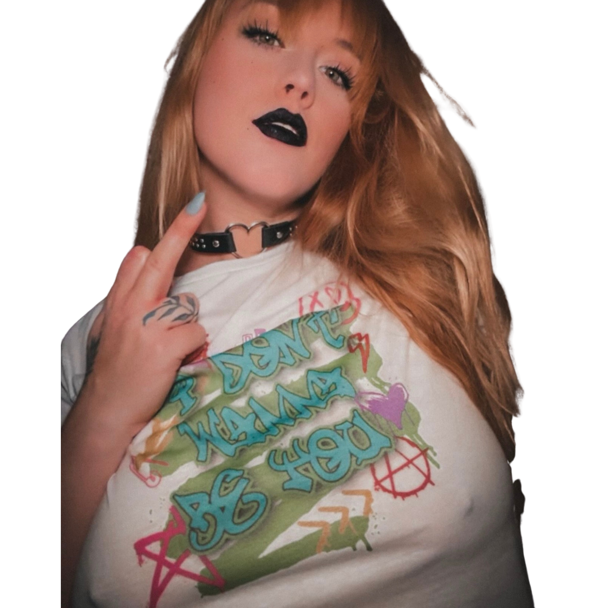 Close-up of a woman with long red hair, wearing dark lipstick, a black choker necklace, and tattoos on her arm, wearing a white T-shirt with colorful text and graphics.