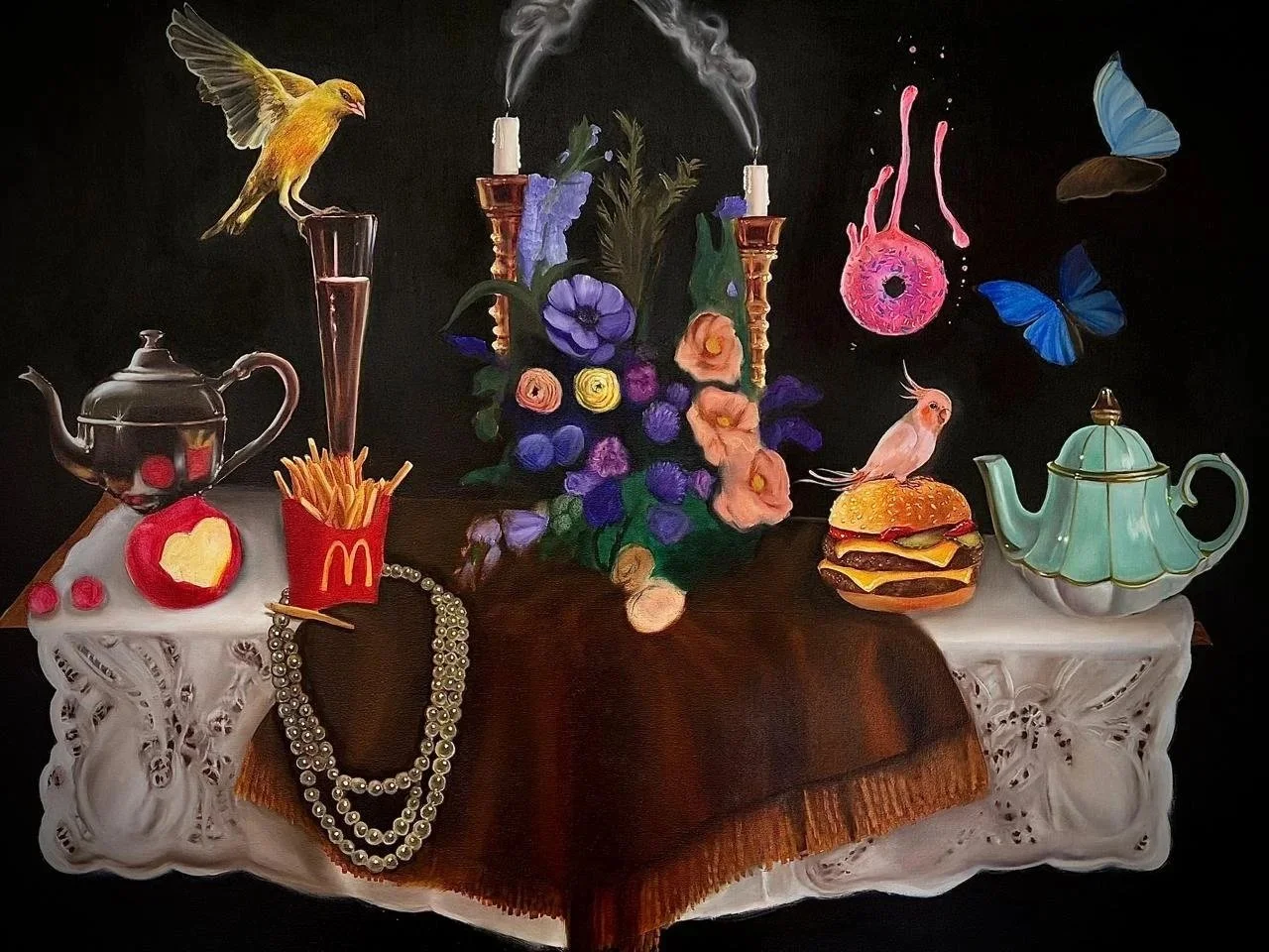 Naturaleza con una mesa decorada con manteles blancos, en el centro una planta con flores moradas, amarillas, rosas, y anaranjadas, rodeada de objetos como una tetera verde, un pastel de hamburguesa, una cadena de perlas, un frasco de papas fritas de McDonald's, un teléfono antiguo, dos candelabros con velas humeantes, un colibrí, mariposas azules y una ave amarilla en un florero.