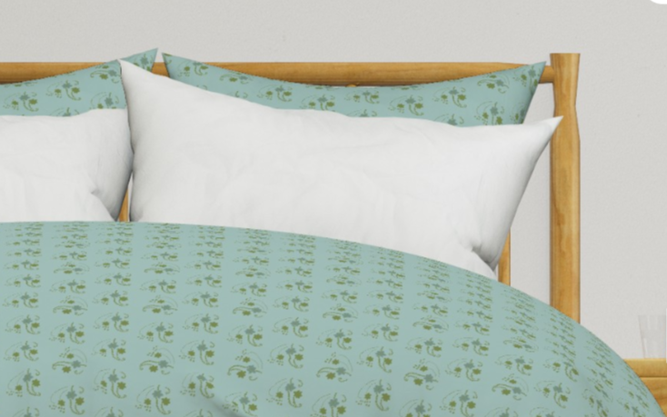 Close-up of a bed with light blue patterned bedding, white pillows, and a wooden headboard.