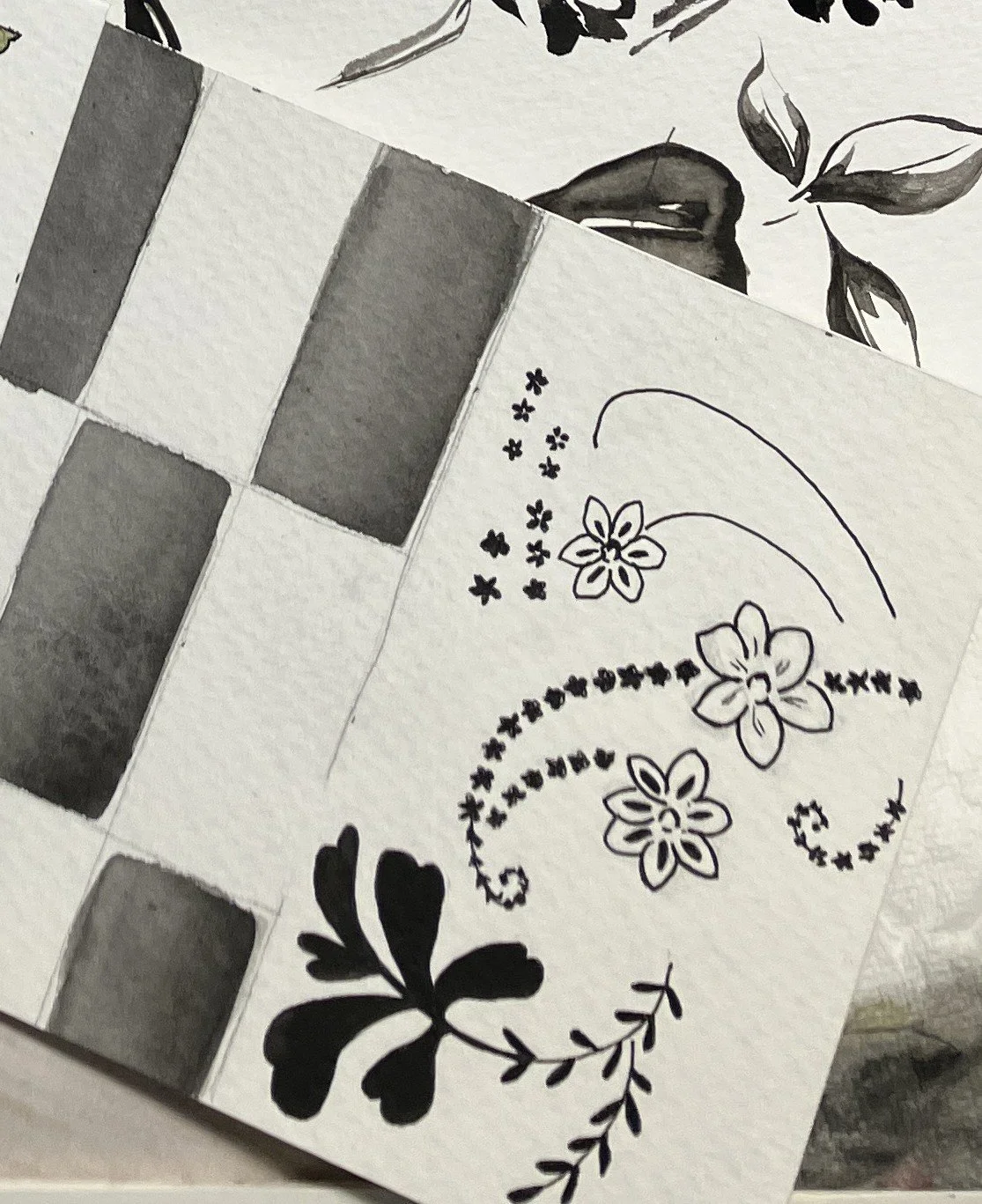 A black and white hand-drawn illustration featuring flowers, leaves, and decorative swirling patterns.