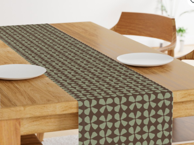 A wooden dining table with a decorative table runner and two white plates.