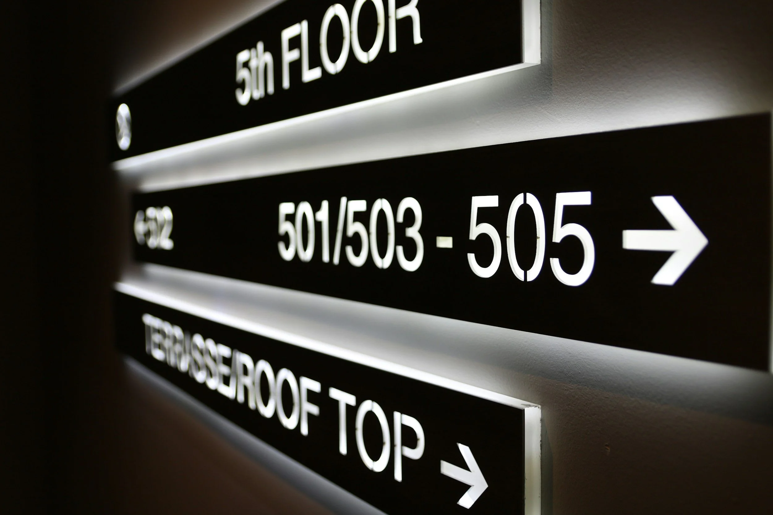 Interior directory sign displaying the 5th floor and other floors with room ranges, illuminated against a dark wall.