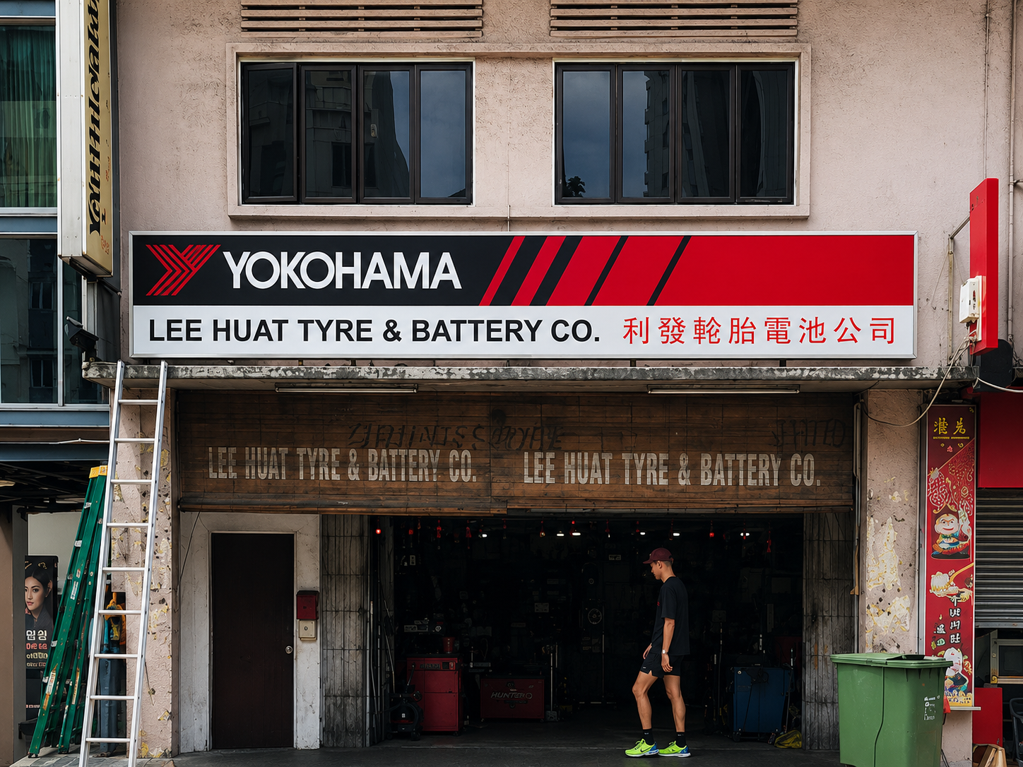 Storefront of Lee Huat Tyre & Battery Co., with a Yamaha sign above, a person walking in front, and ladders on the left side