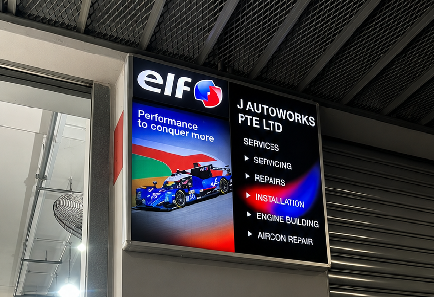 Signboard for J Autoworks PTE Ltd showing services such as servicing, repairs, installation, engine building, and aircon repair, with an advertisement for elf performance motorsports.