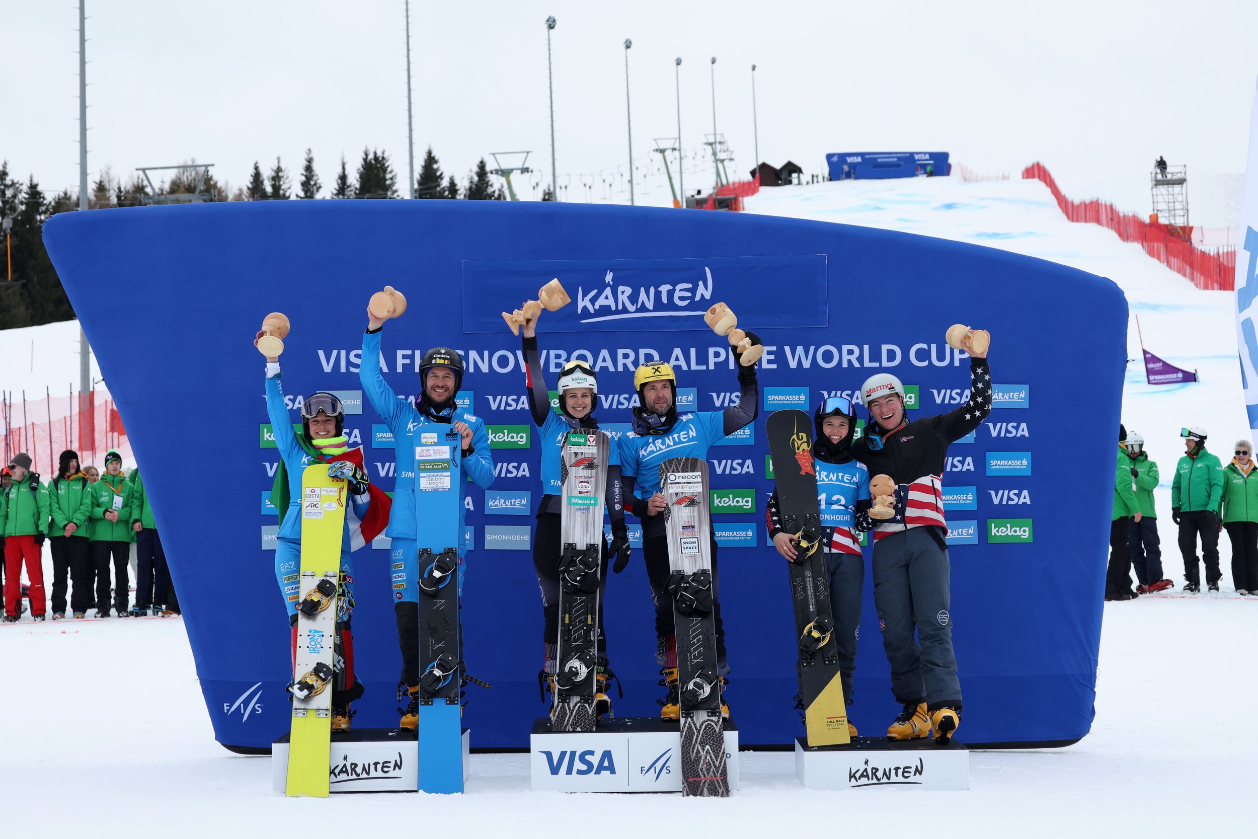 Group of six snowboarders celebrating winners' podium at a snowboarding event in Carinthia during the FIS World Cup.