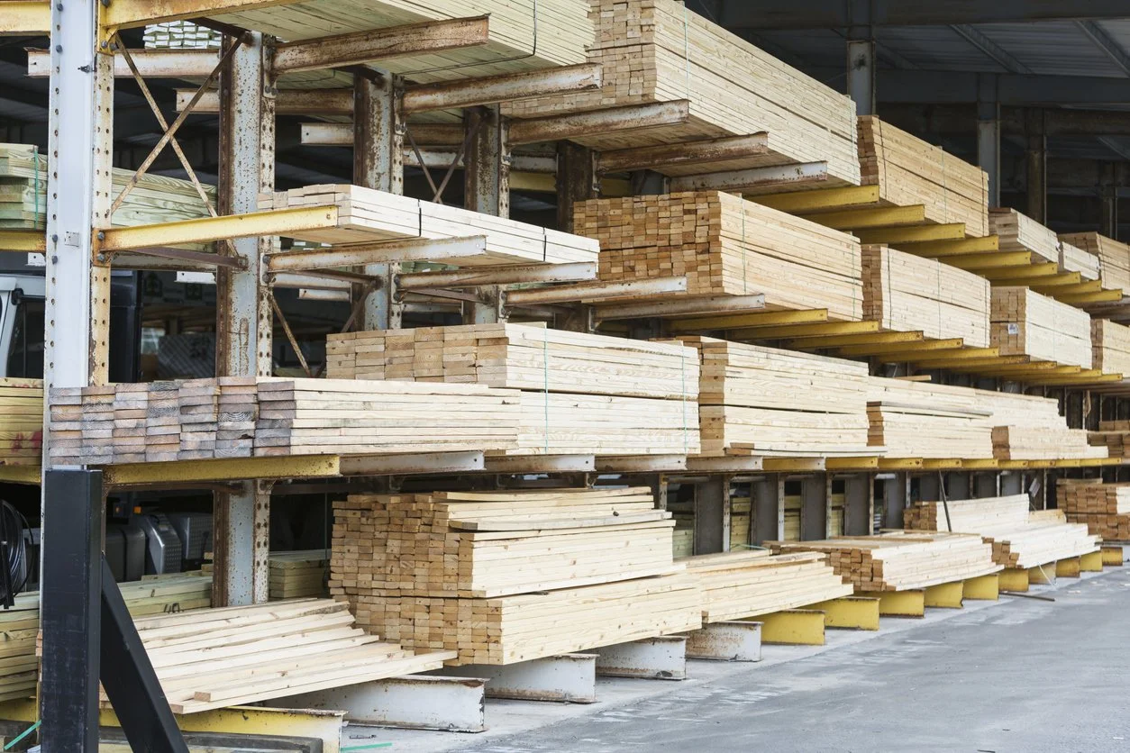 Wood planks and lumber stacked on metal shelves inside a hardware store or warehouse.