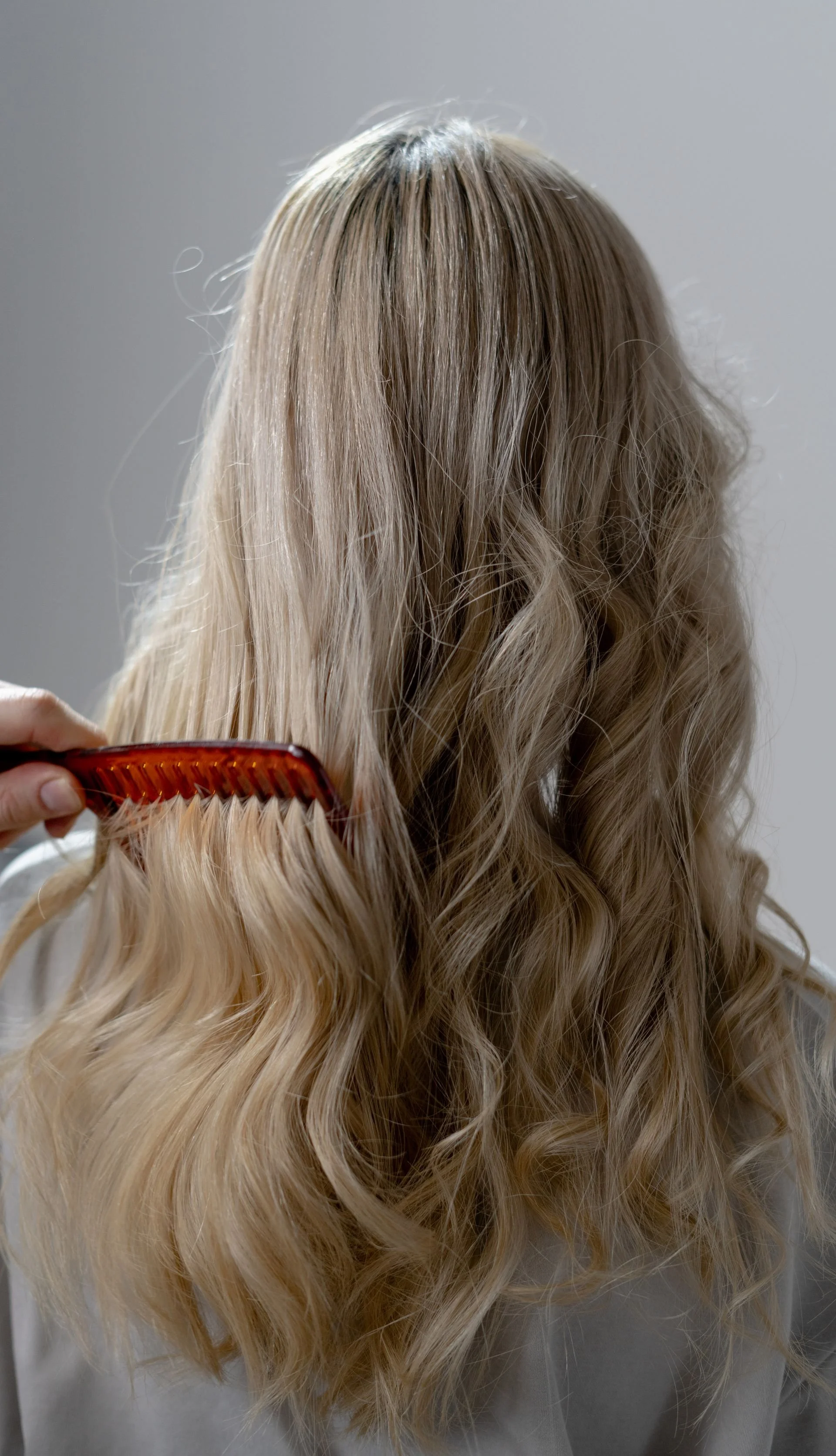 Client with long blonde wavy hair extensions styled at a hair salon in Denver, NORTH CAROLINA