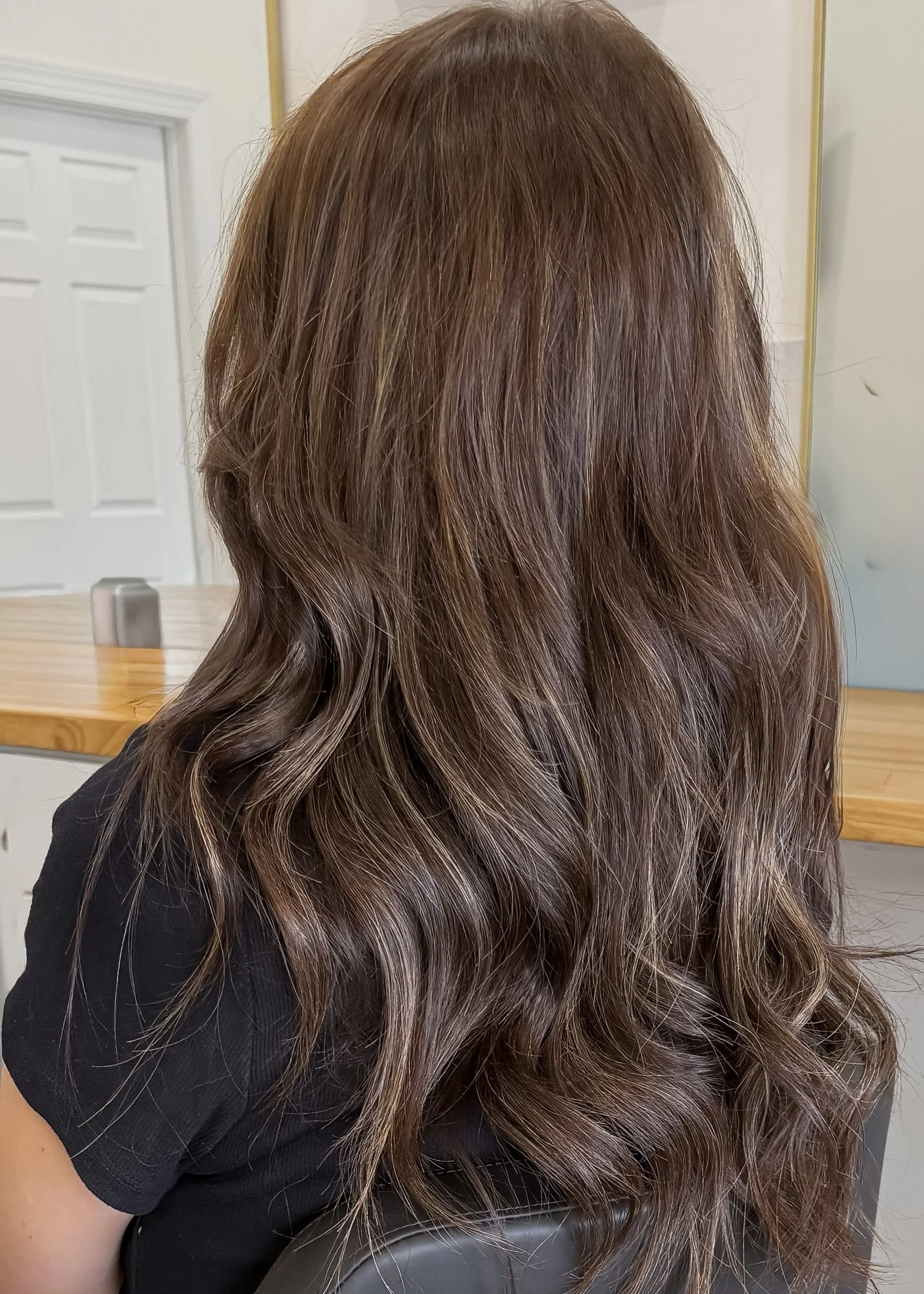 Back view of a woman with wavy, 18 inch hair extensions, hand tied