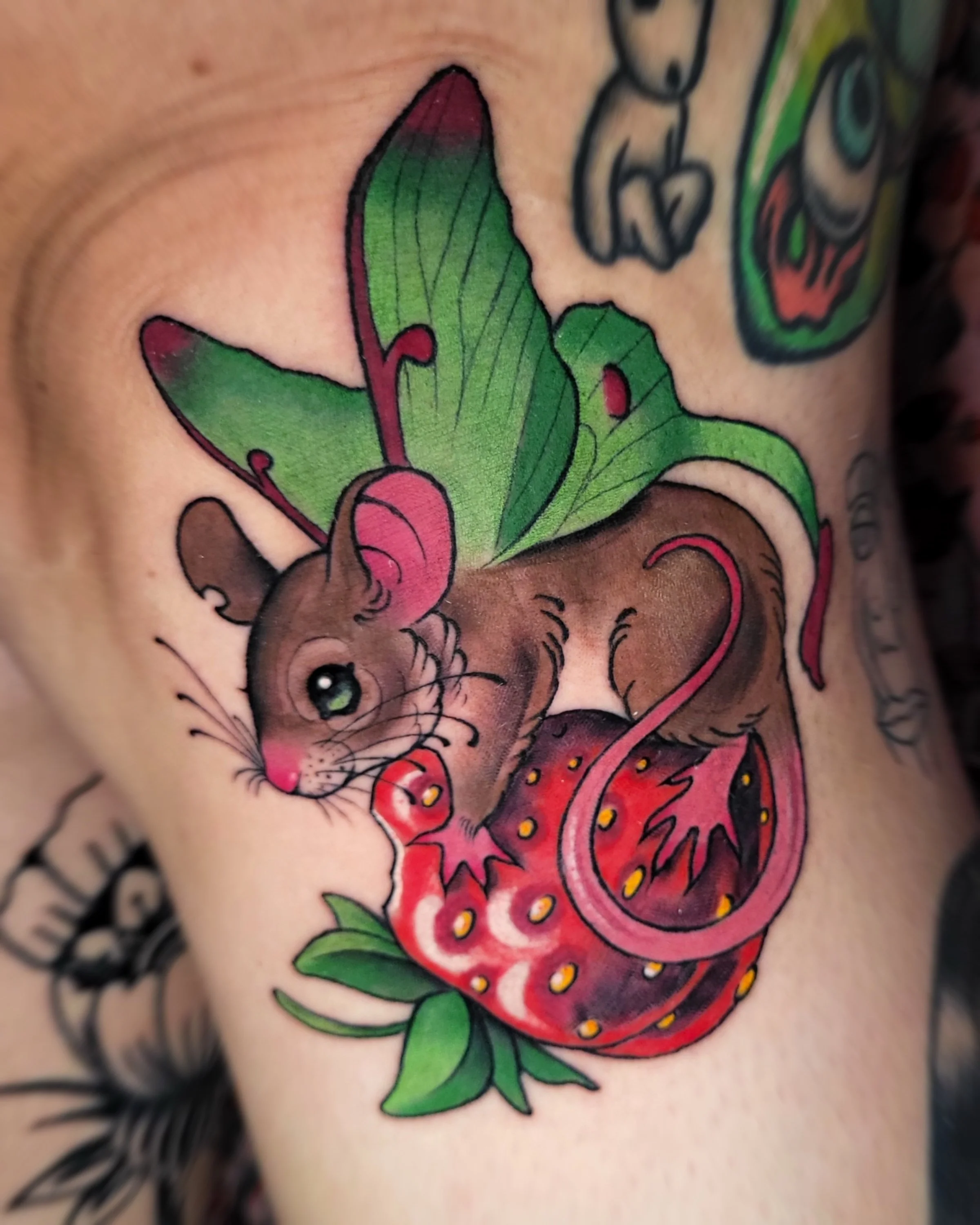 Close-up of a colorful traditional tattoo of a rose with green leaves on skin.