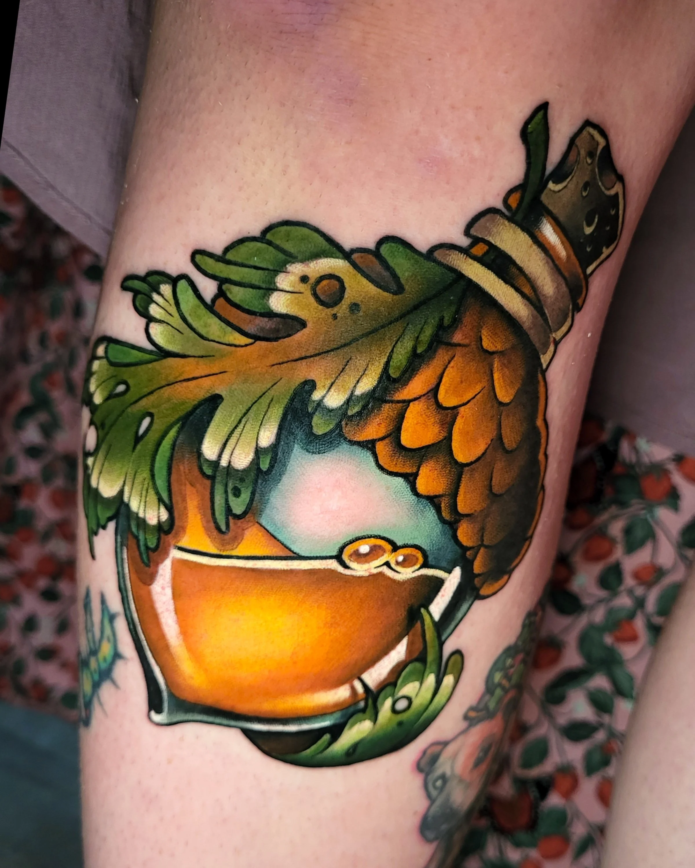 Close-up of a tattoo of a colorful butterfly on person's skin, with detailed wings and vibrant orange, green, and black colors.