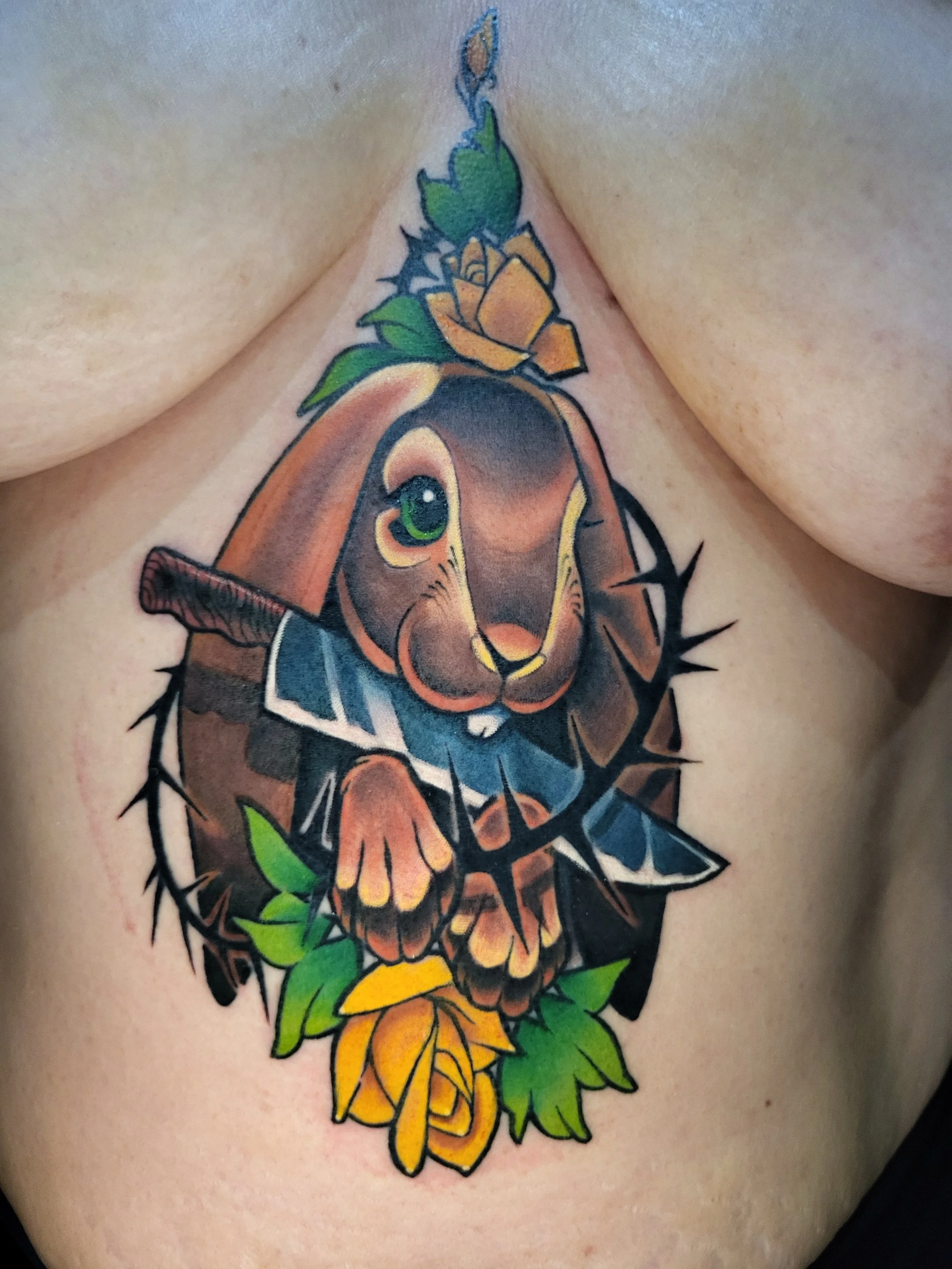 Colorful tattoo of a deer with a yellow flower, green leaves, a yellow butterfly, and black spines.