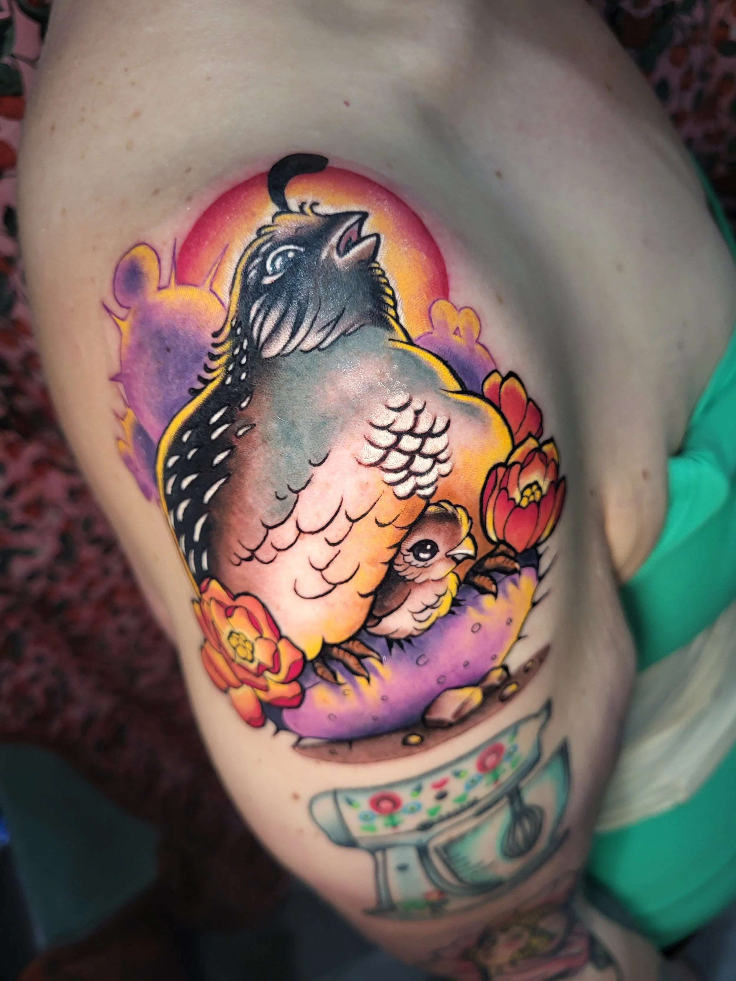 Colorful tattoo of a bird with open beak, surrounded by flowers, with a sunset or sunrise in the background.