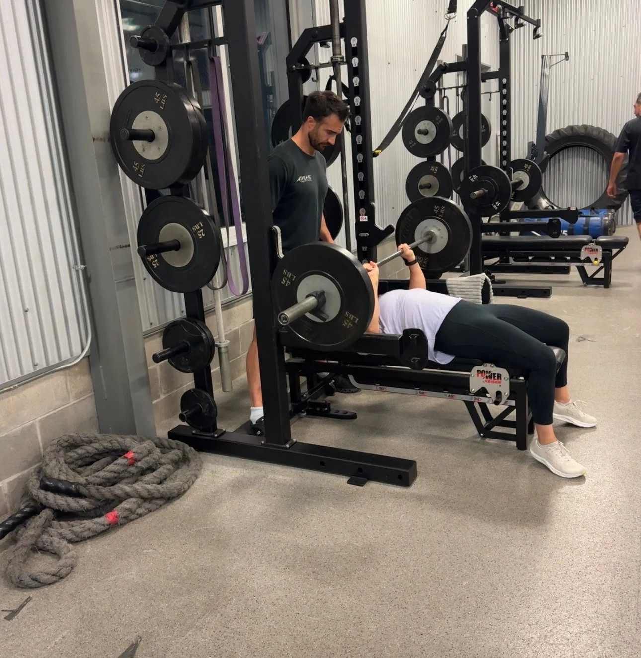 Coach Rob Tapia spotting a client on the bench press at a Houston gym