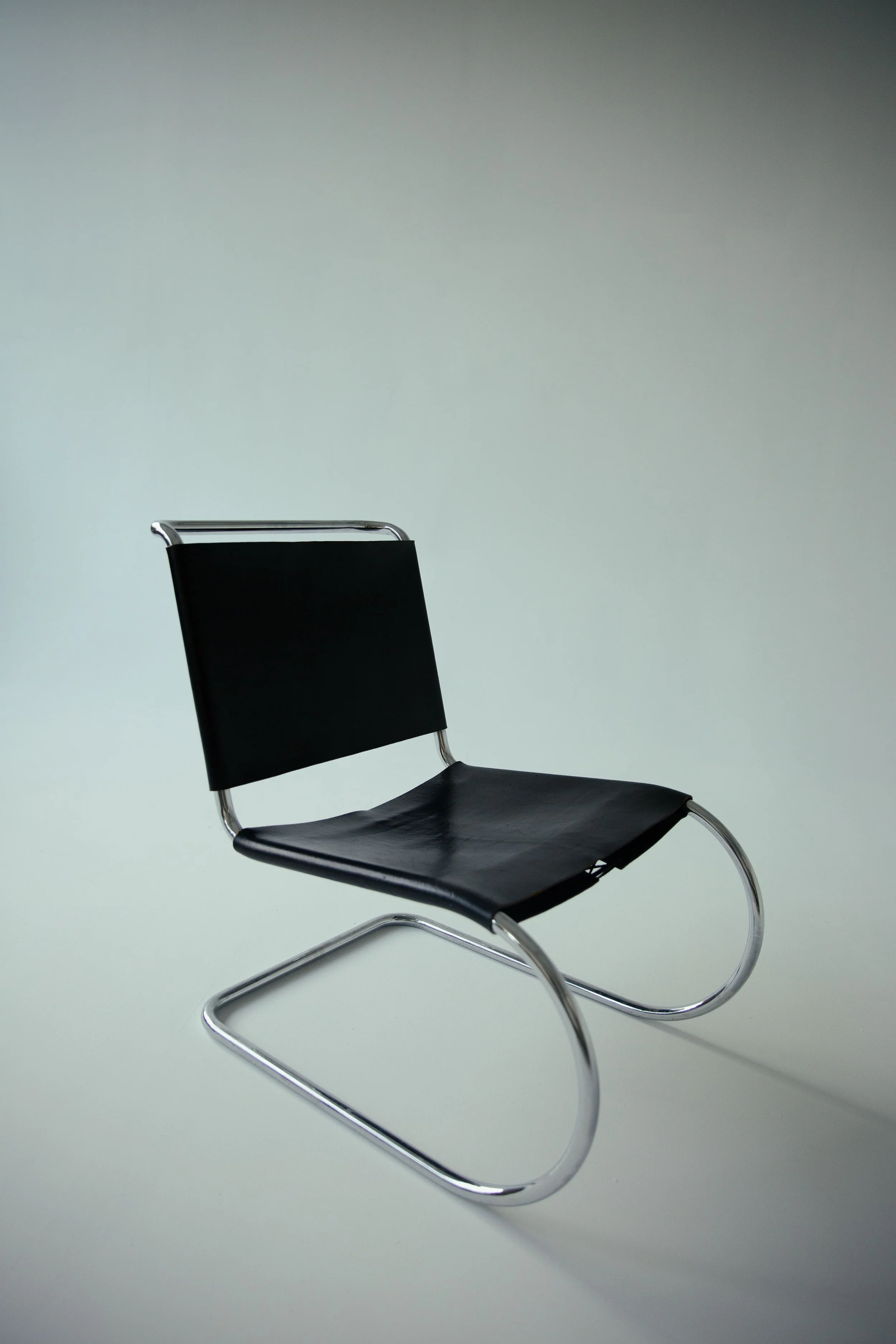 A modern black chair with a metal frame and curved legs, set against a plain, light-colored background.