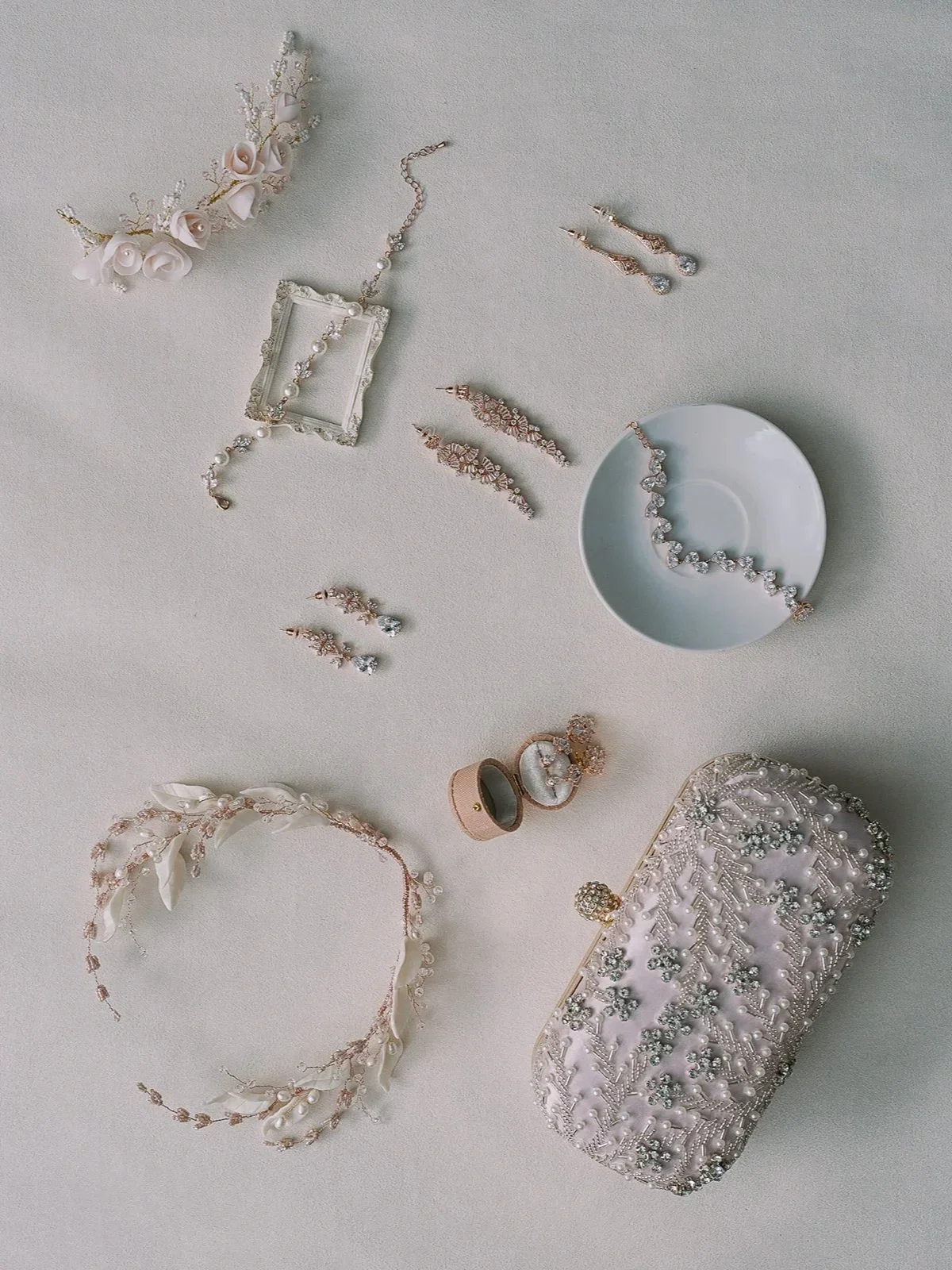 Elegant jewelry including necklaces, earrings, rings, and a clutch purse, displayed on a white surface.