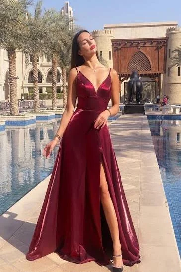 Woman in a deep red gown with a thigh-high slit, standing by a pool with palace-like architecture in the background.