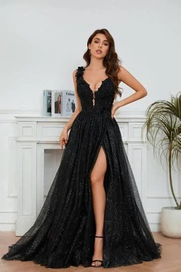 Woman in a black, glittery gown with a thigh-high slit, standing in front of a white fireplace mantel and a potted plant.