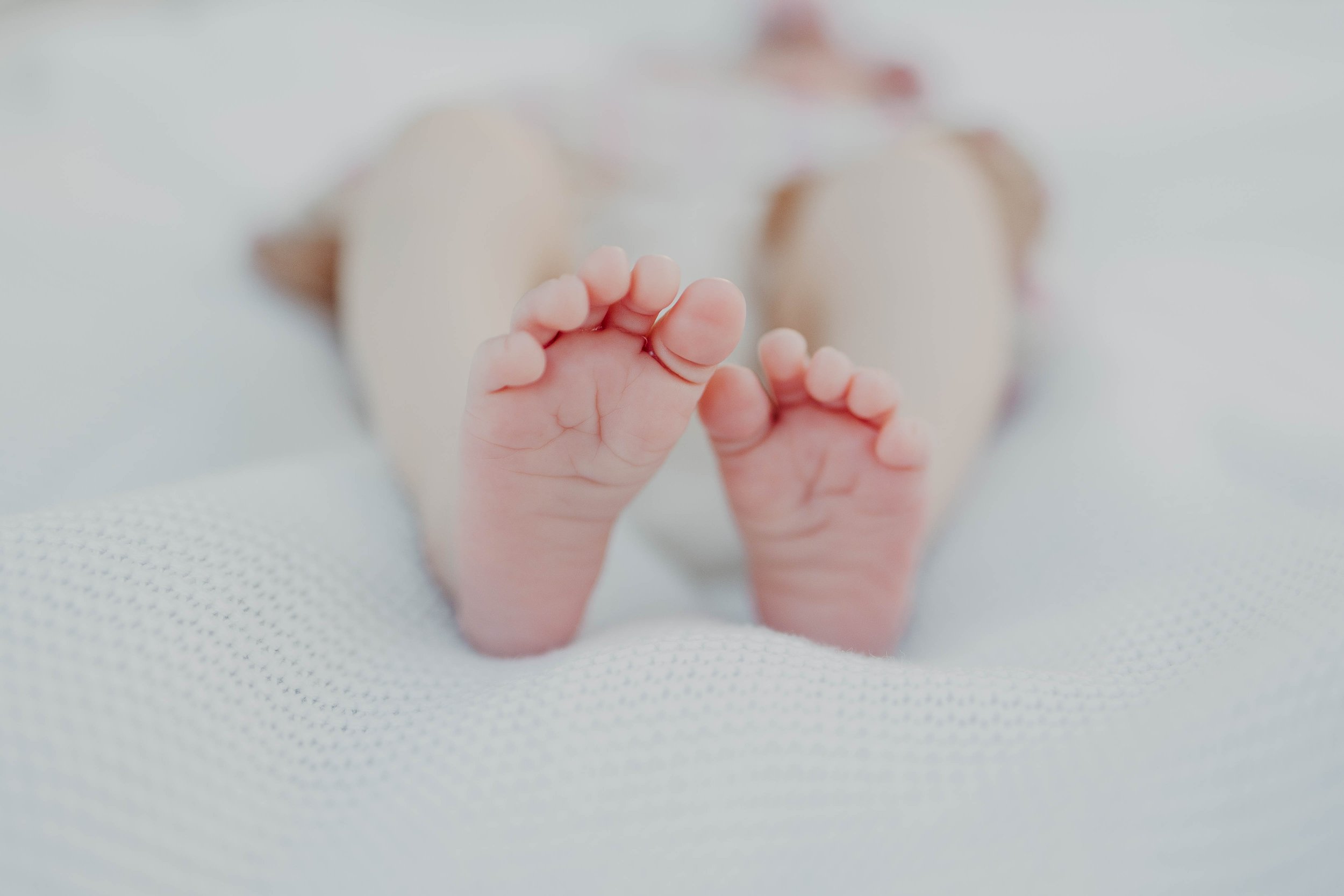 Close-up of a newborn baby's feet, with a blurred background.