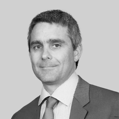 Black and white photo of a man in a business suit smiling slightly, facing forward.