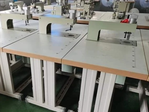 Multiple industrial sewing machines on work tables in a factory
