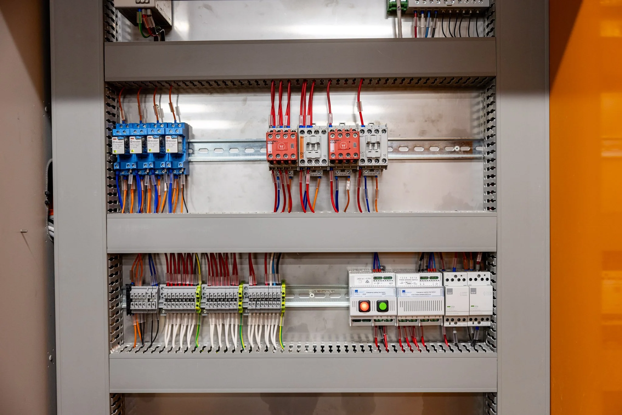 An electrical control panel containing various circuit breakers, relays, and wiring organized inside a metal enclosure.
