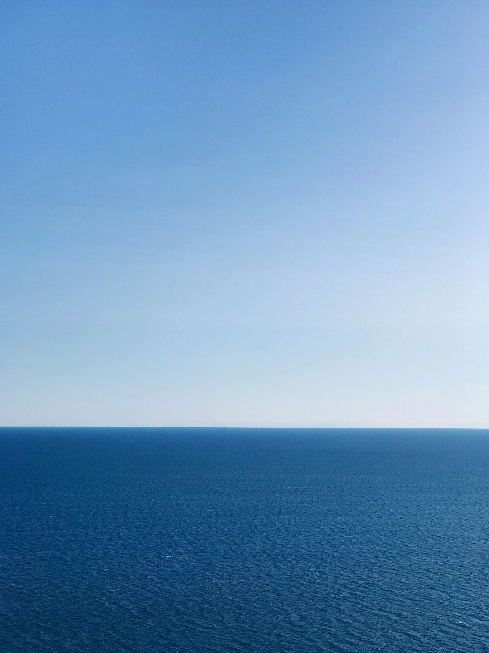 Das Bild zeigt einen klaren Himmel, der ins Wasser übergeht, mit einer horizontalen Linie, die den Himmel und den Ozean trennt.