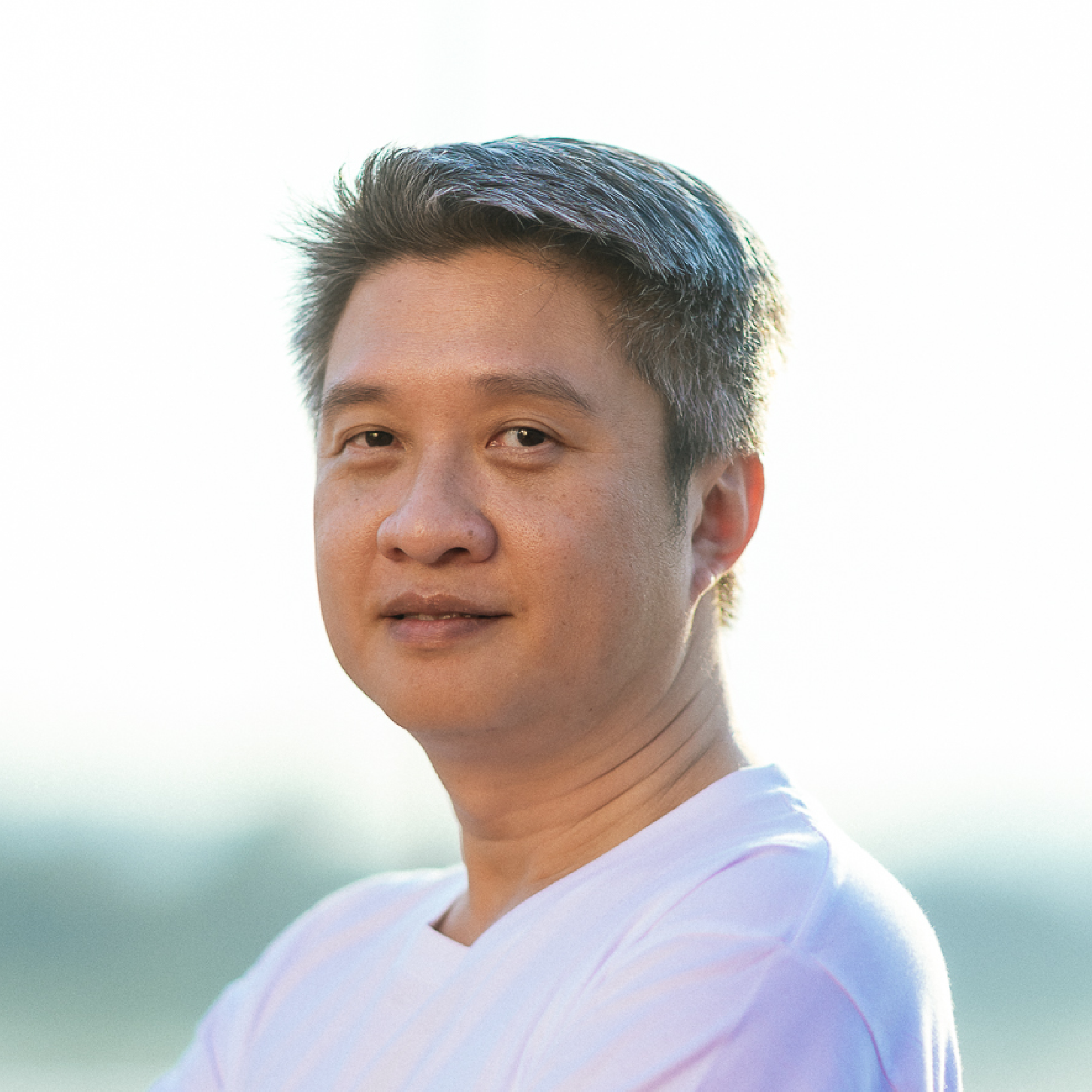 Close-up of Weiyong Kuah, wearing a white shirt, against a gradient background.