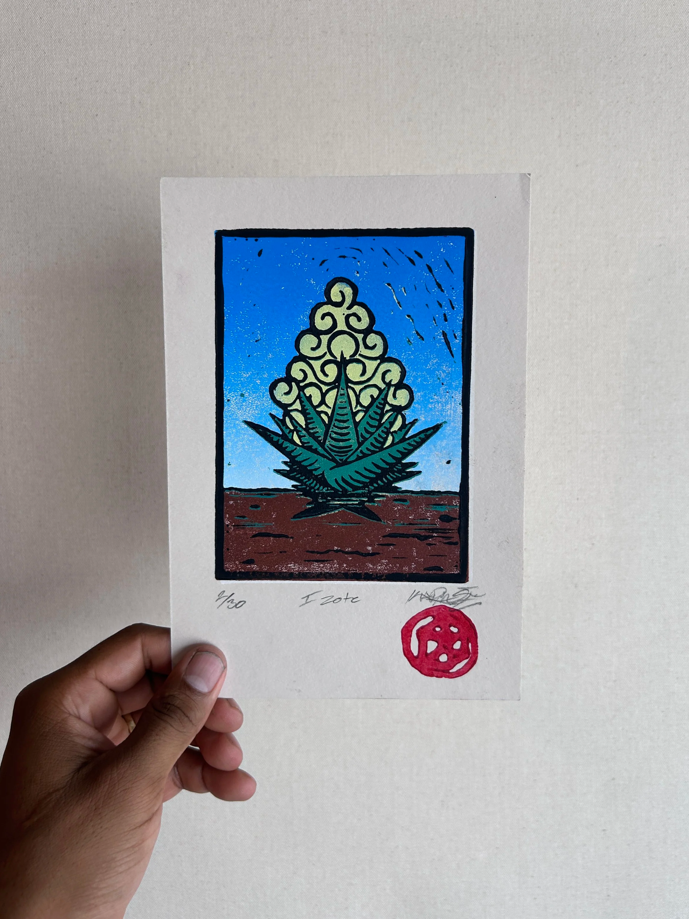 Hand holding a signed limited edition art print of a mystical plant in a card format, with red stamp at the bottom.