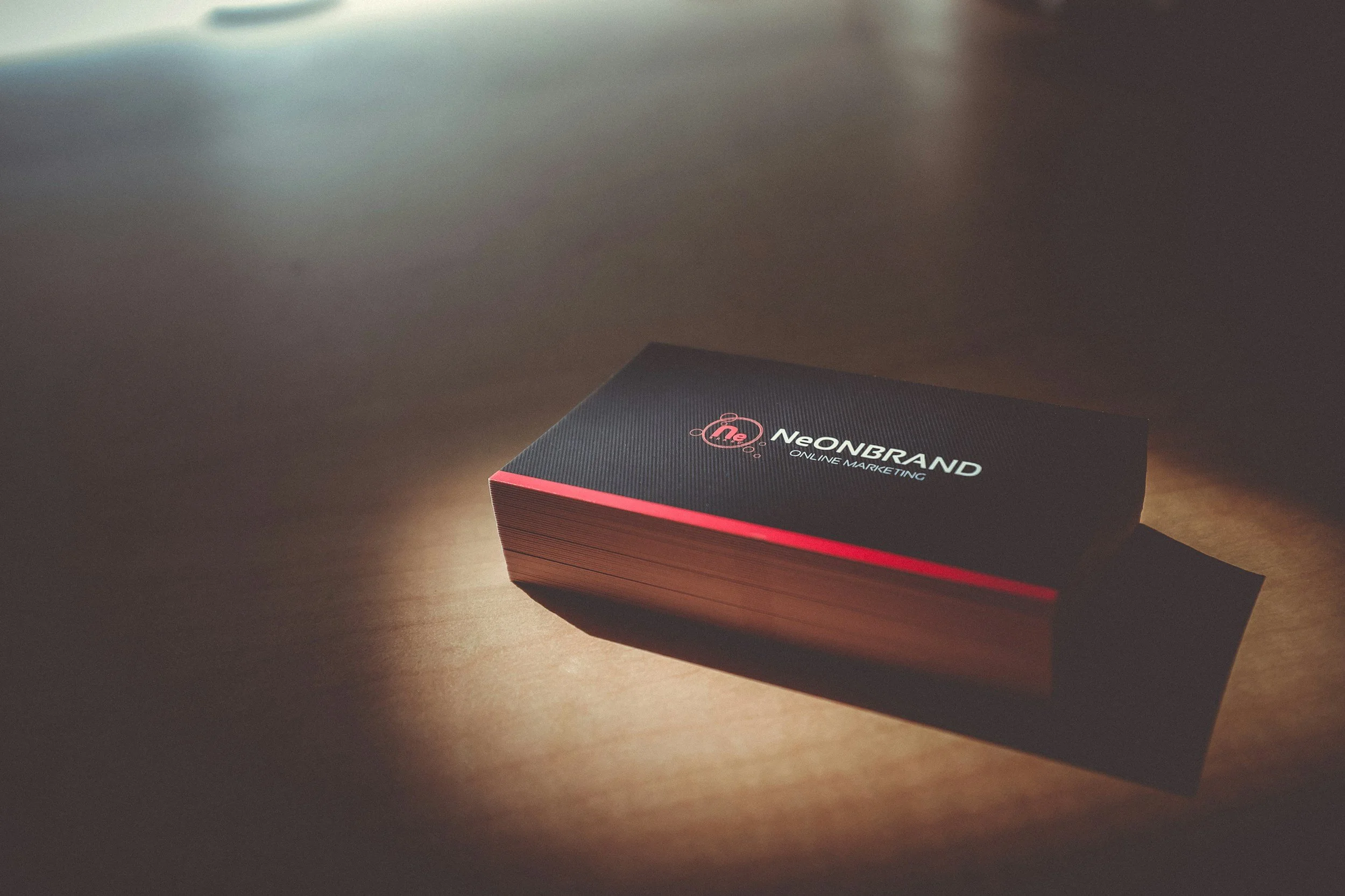 A black box with red accents and the logo 'NeONBRAND' along with the text 'Online Marketing' on it, placed on a wooden surface.