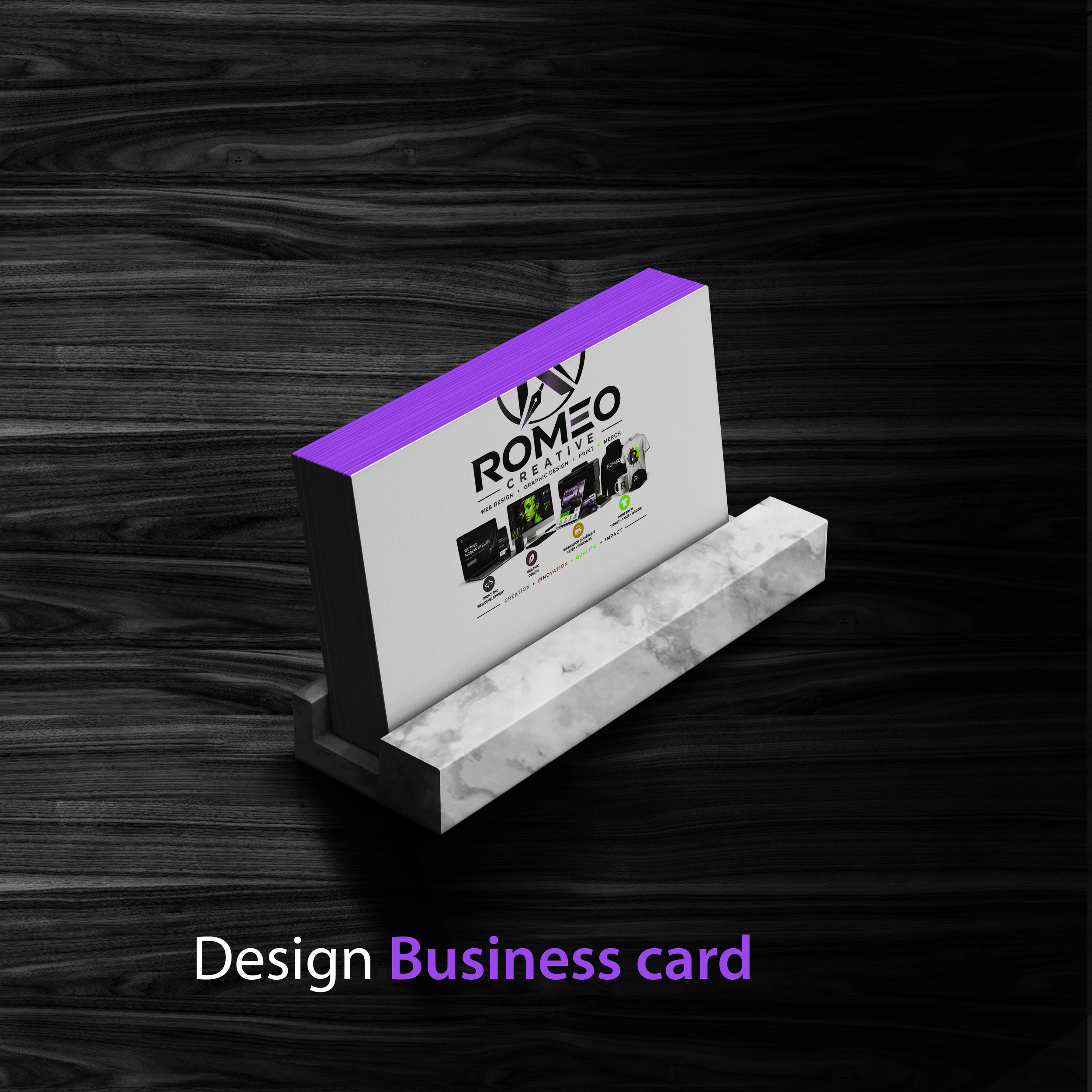 A design business card with a white background, purple accents on the edges, featuring the logo and text for Romeo Creative, indicating services like graphic design, web design, print, and merchandise, placed on a dark wooden surface with a marble block underneath.