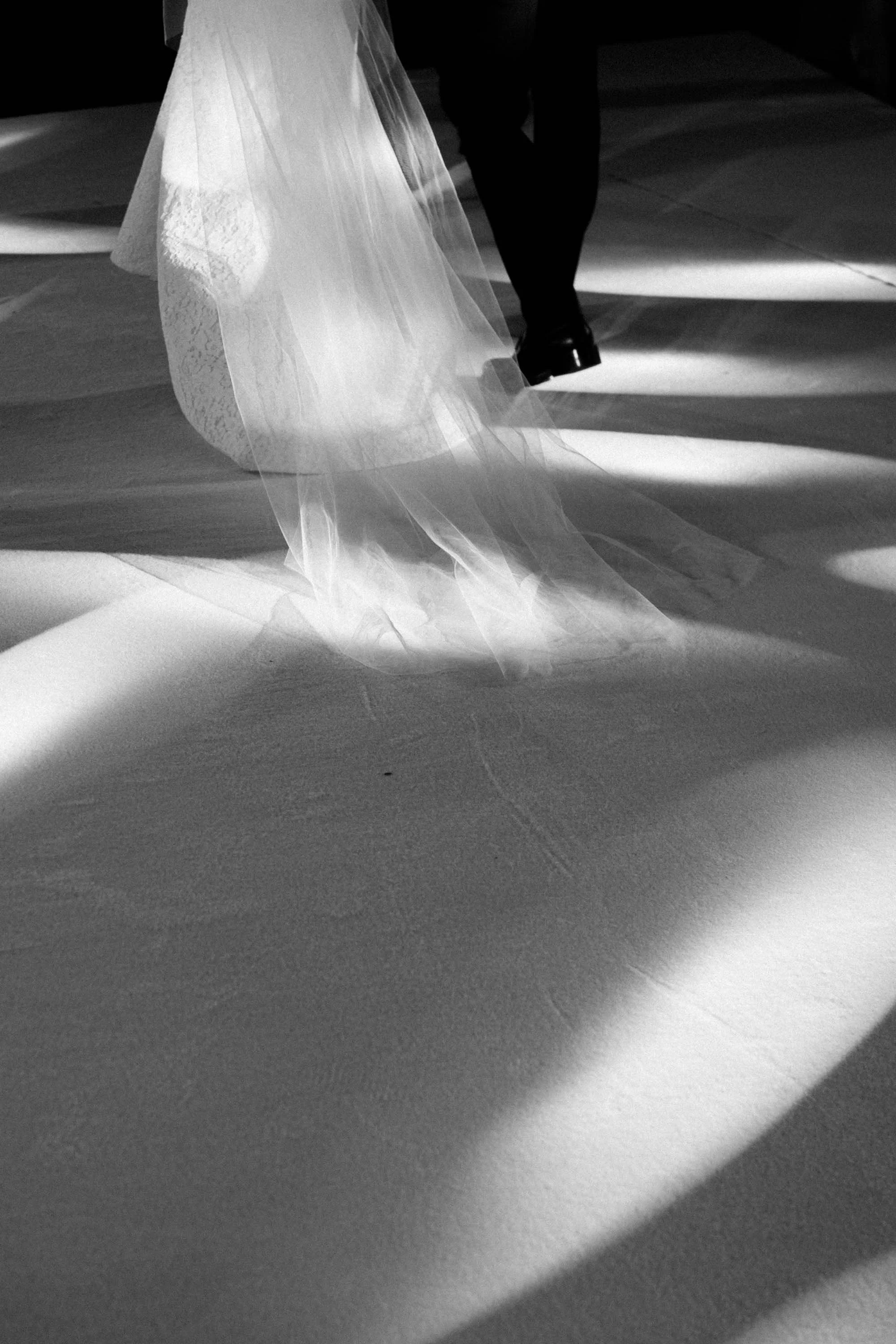 Close-up of the bride and groom walking beneath dramatic lighting.
