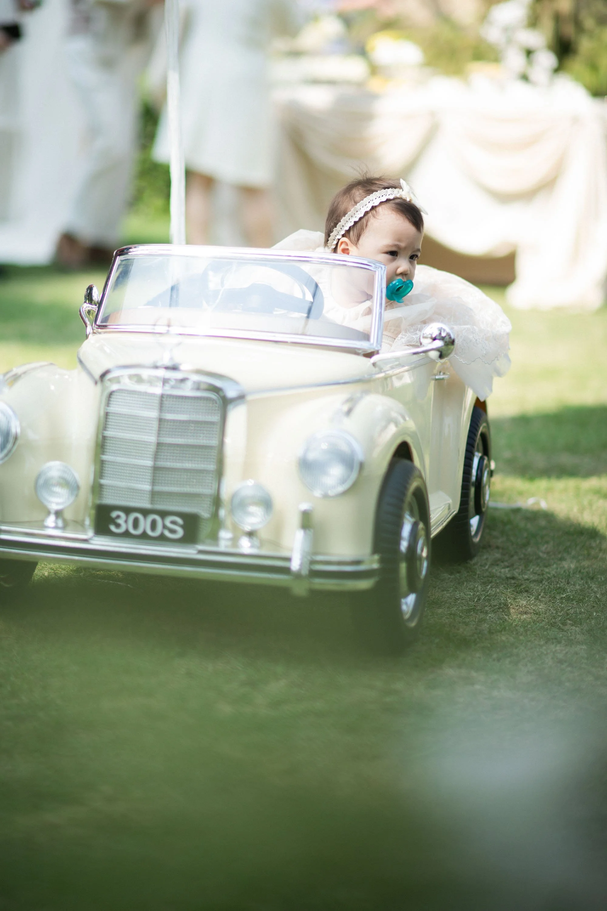 Young flower girl arriving in a toy car carrying the wedding rings.