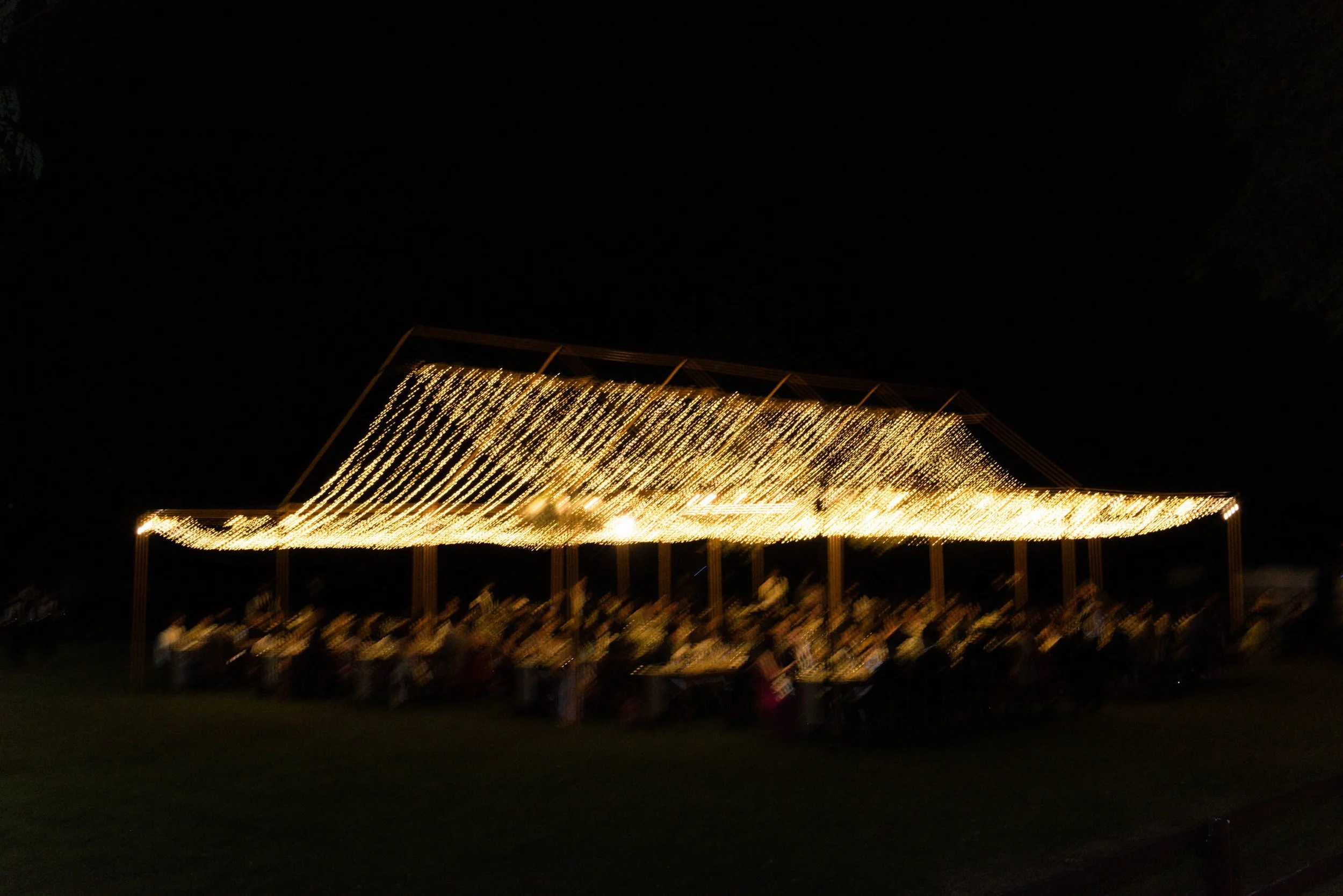 Wide view of the dinner setting illuminated by string lights at night.