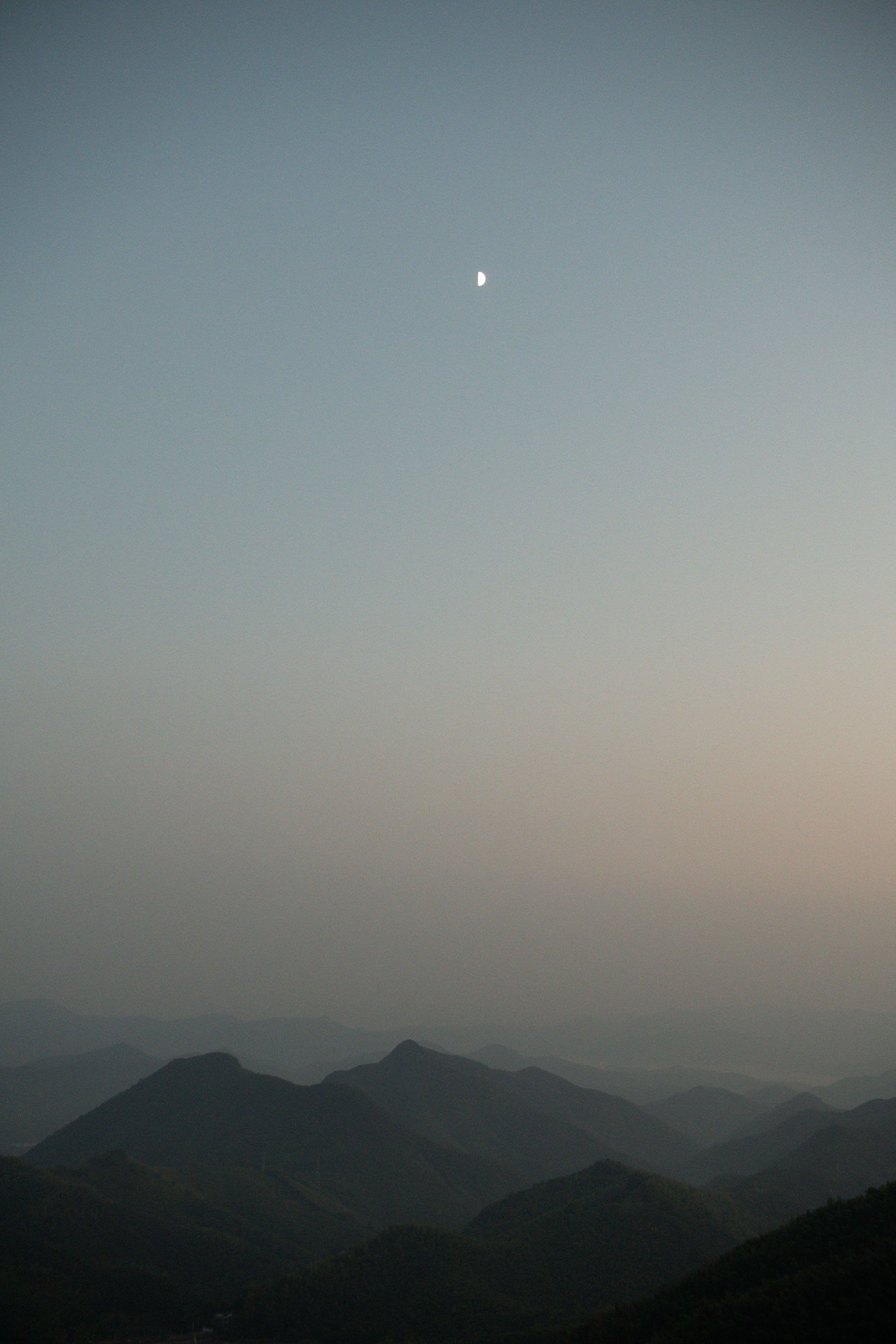 Evening view of the mountains with the moon rising above the landscape.