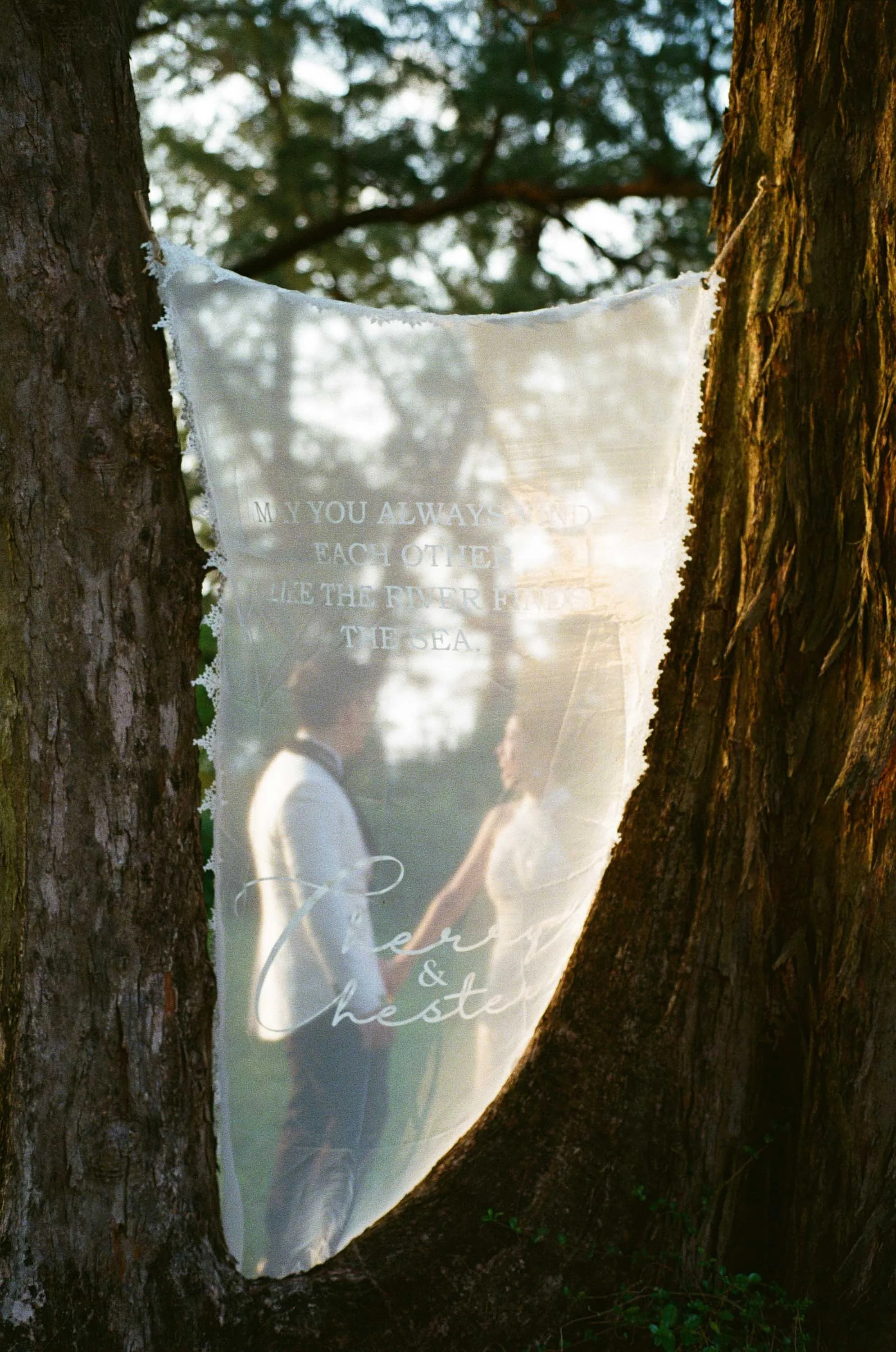 Bride and groom standing beside their wedding fabric sign.