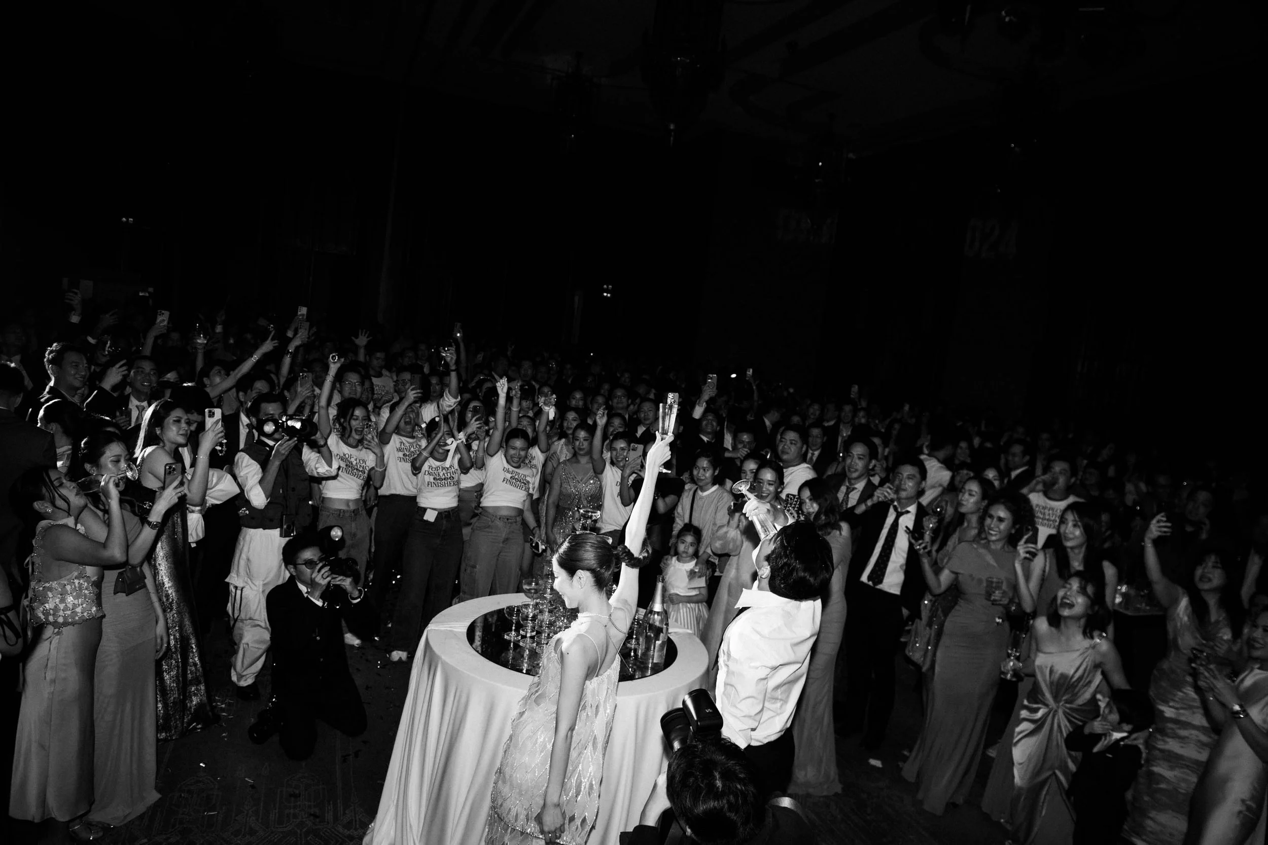 Bride and groom raising a toast with guests after pouring the champagne tower.