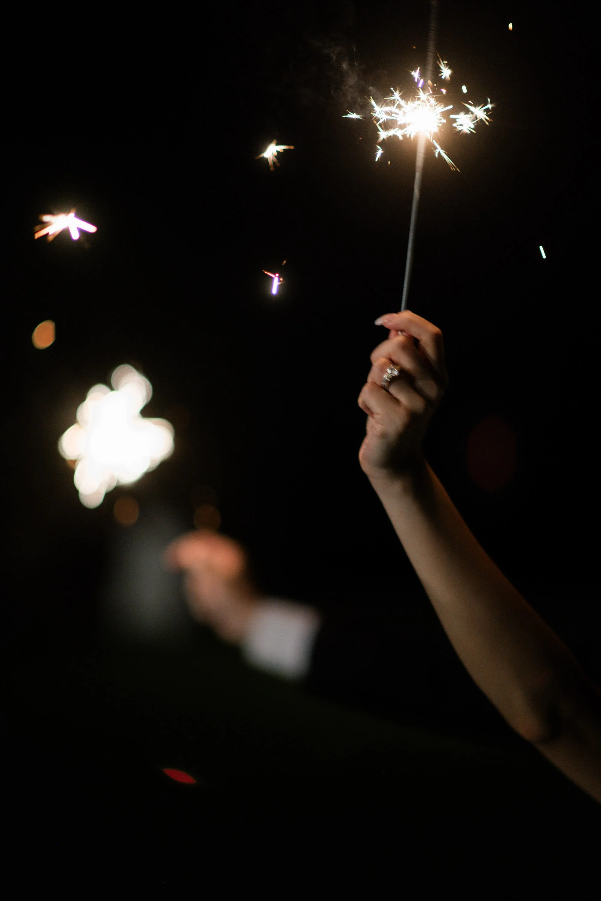 Bride and groom holding sparklers before the reception entrance.