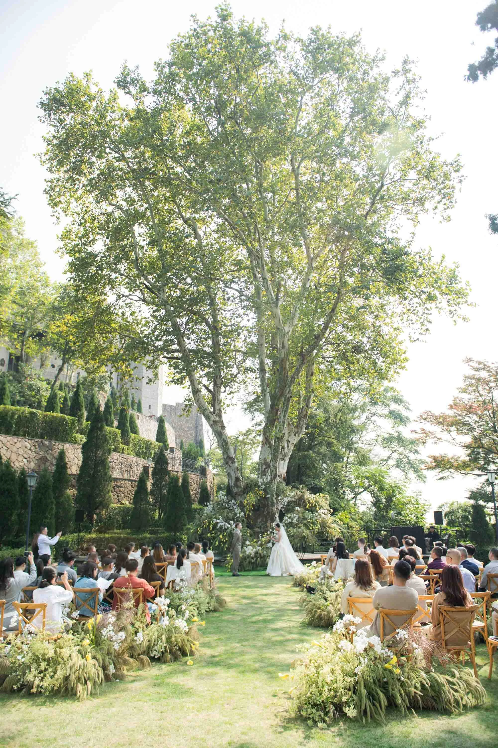 Outdoor wedding ceremony surrounded by trees and mountain views at Naked Castle Moganshan.