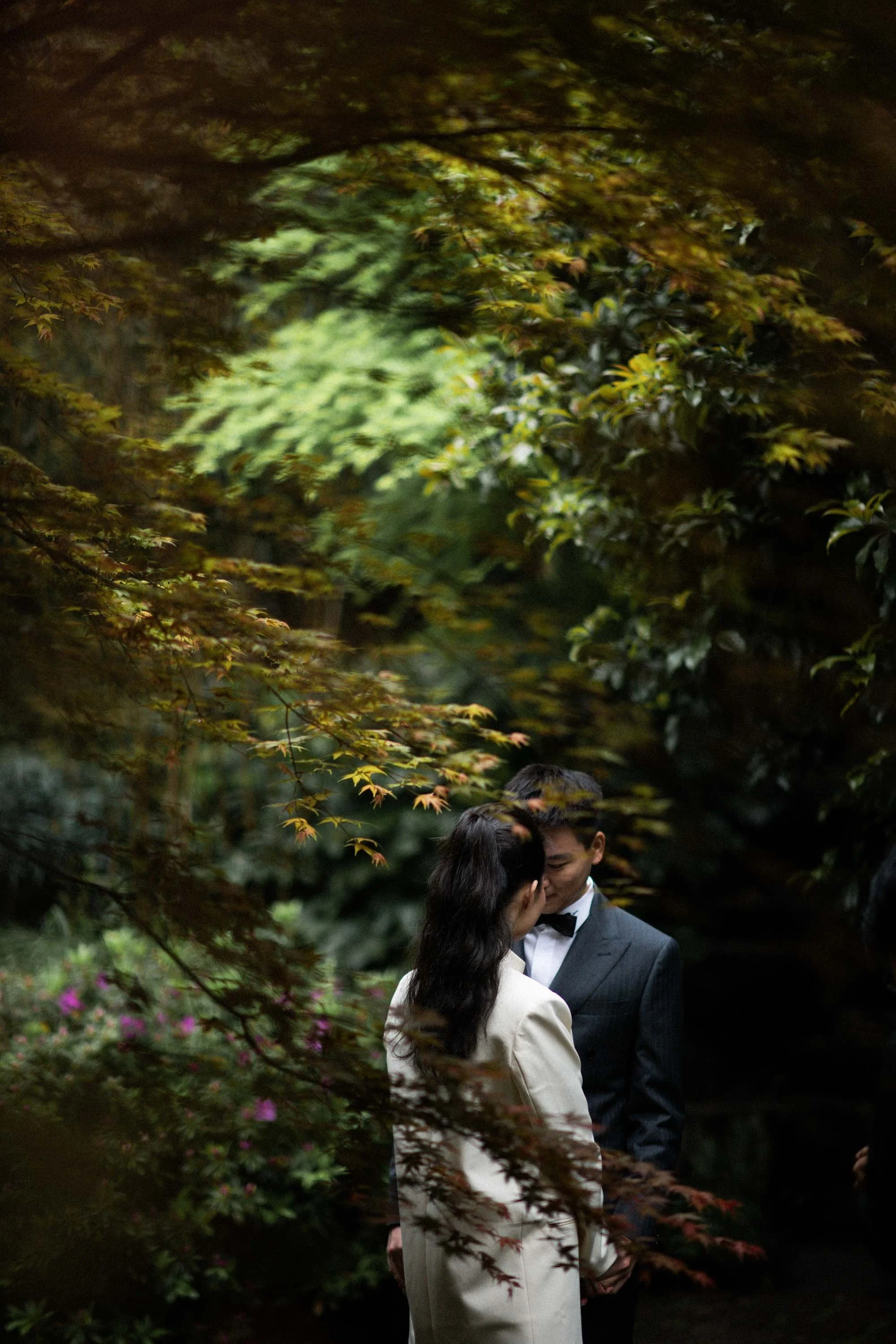 Bride and groom surrounded by autumn foliage.