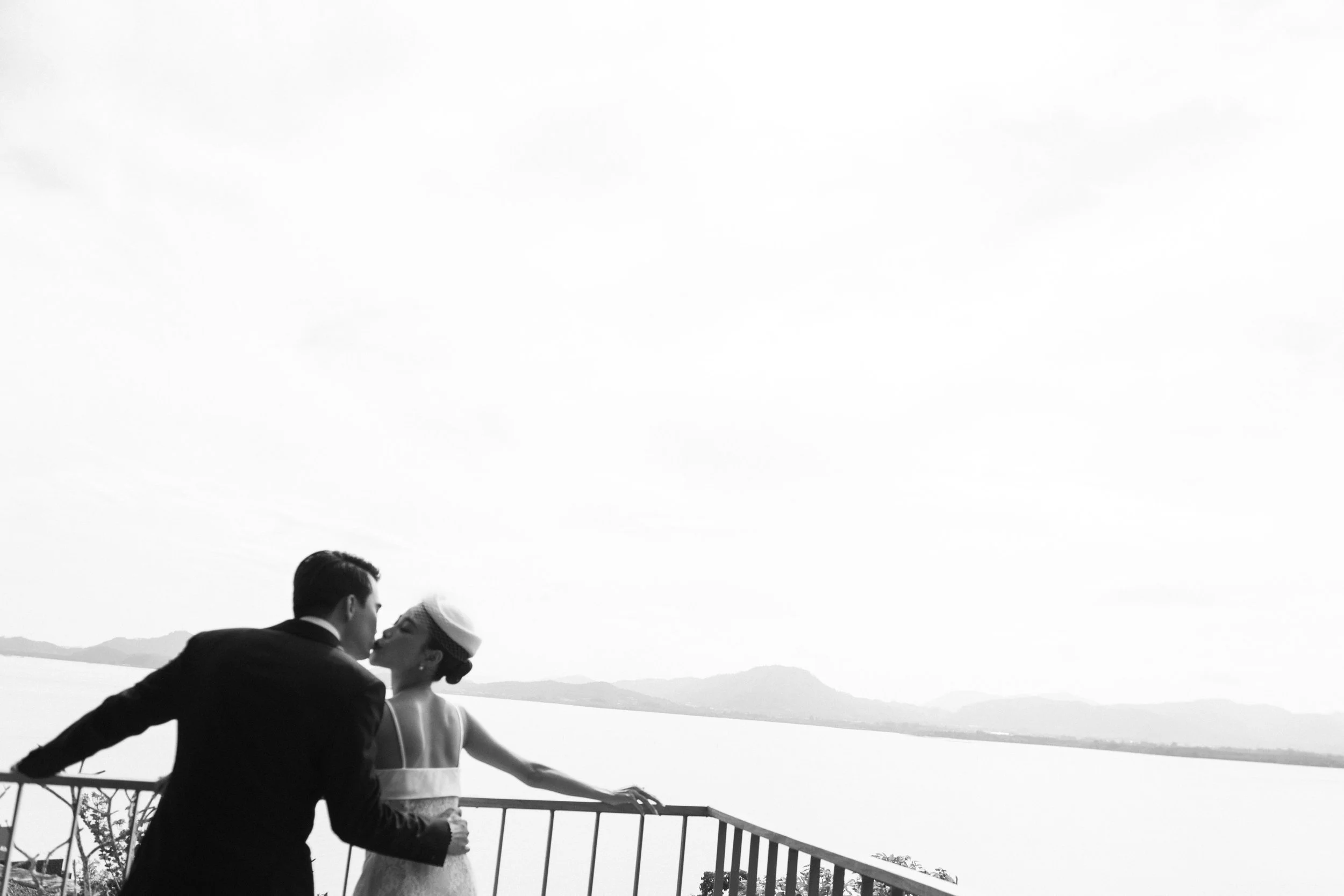 Bride and groom sharing a kiss overlooking the ocean.
