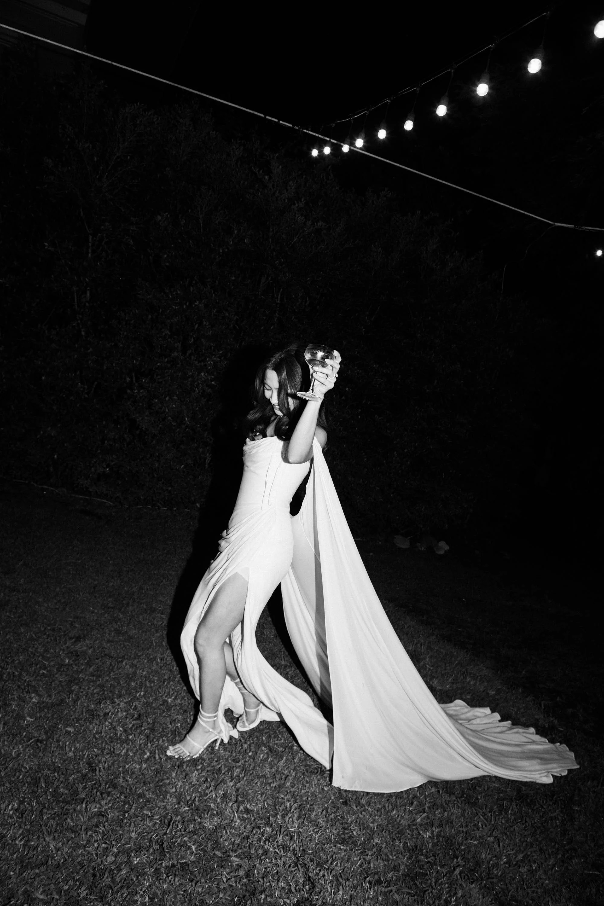 Bride walking with a glass of champagne during the evening celebration.