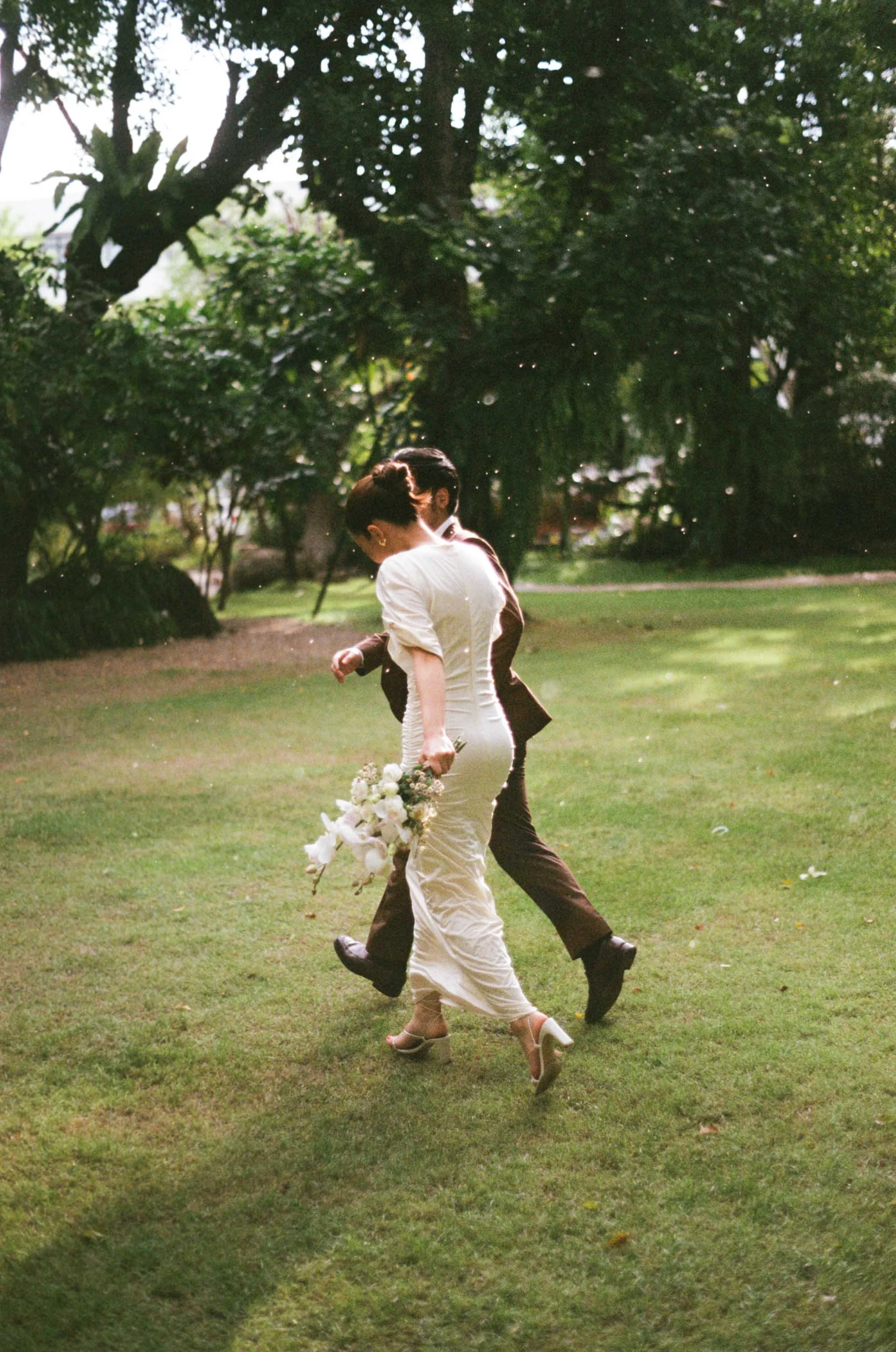 Couple running across the lawn through the rain to find shelter.