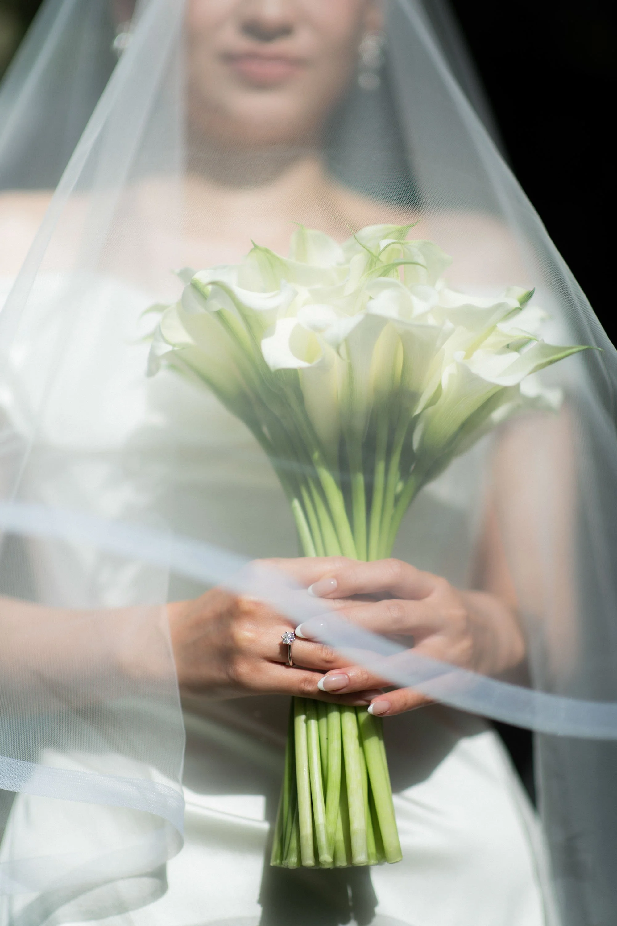 Bride holding her bouquet beneath her veil before the ceremony.