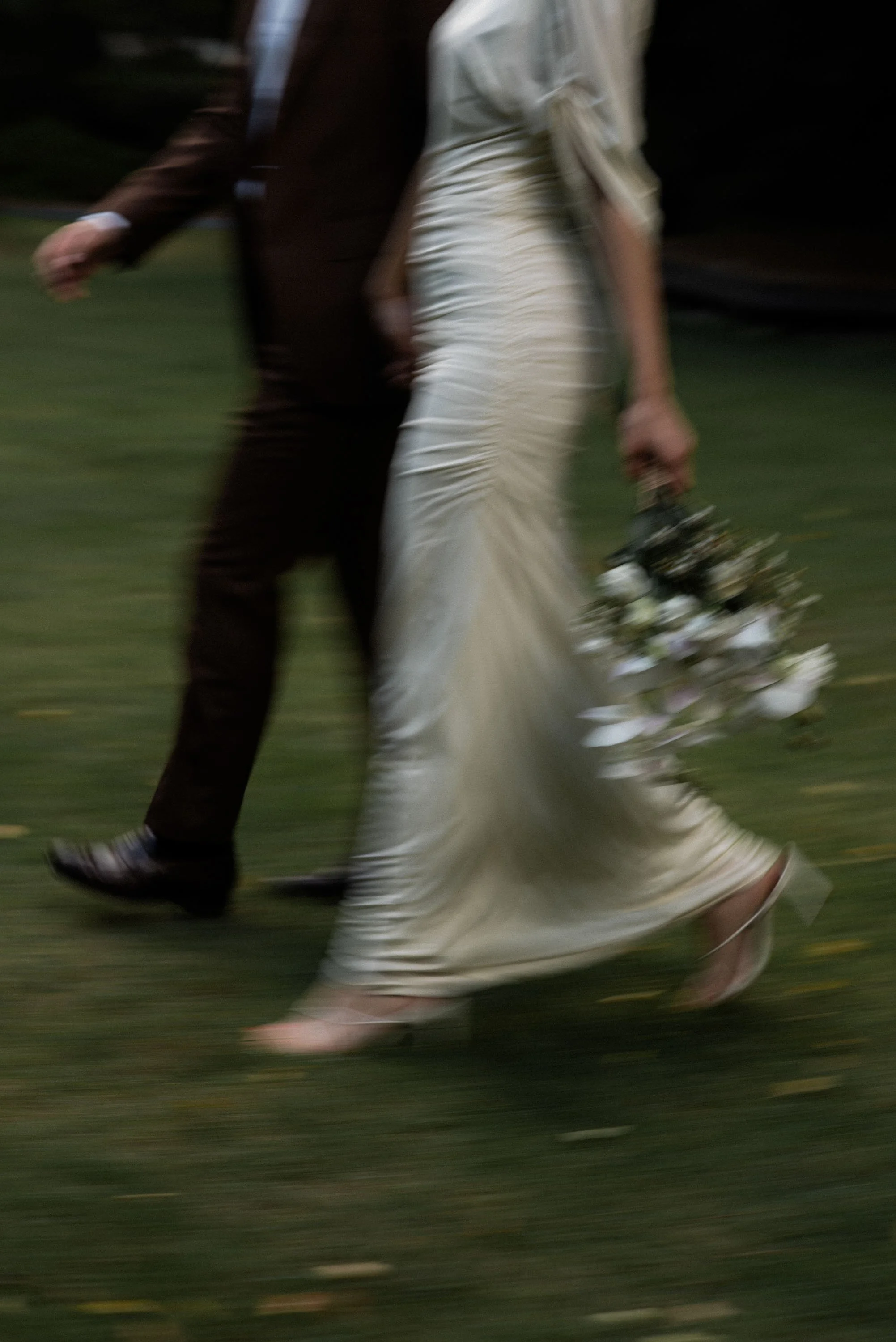 Close-up of the couple walking together with the woman's bouquet swinging beside her.