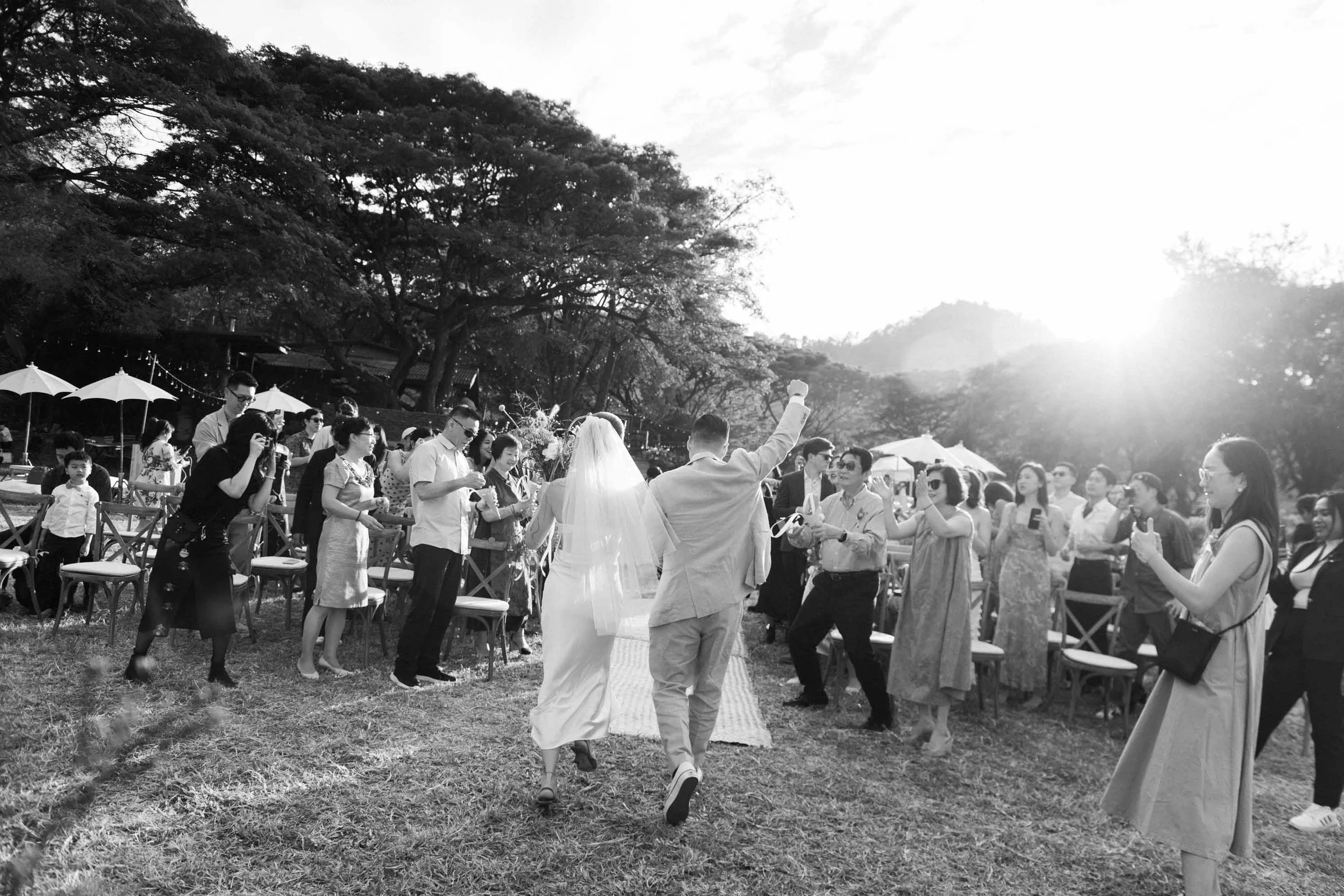 Bride and groom walking back down the aisle as guests cheer and toss flower petals.