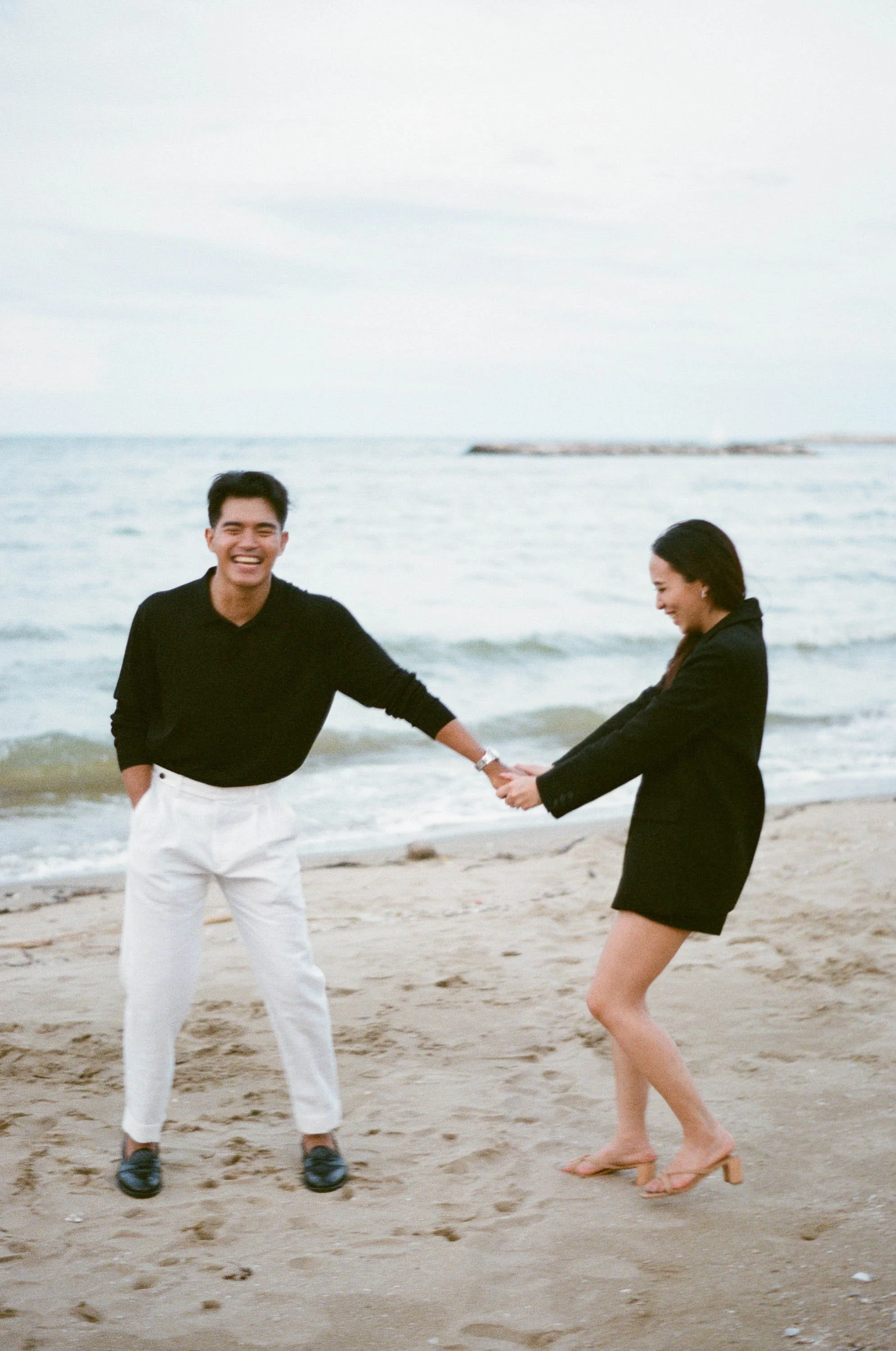 Couple laughing together as they walk along the beach.