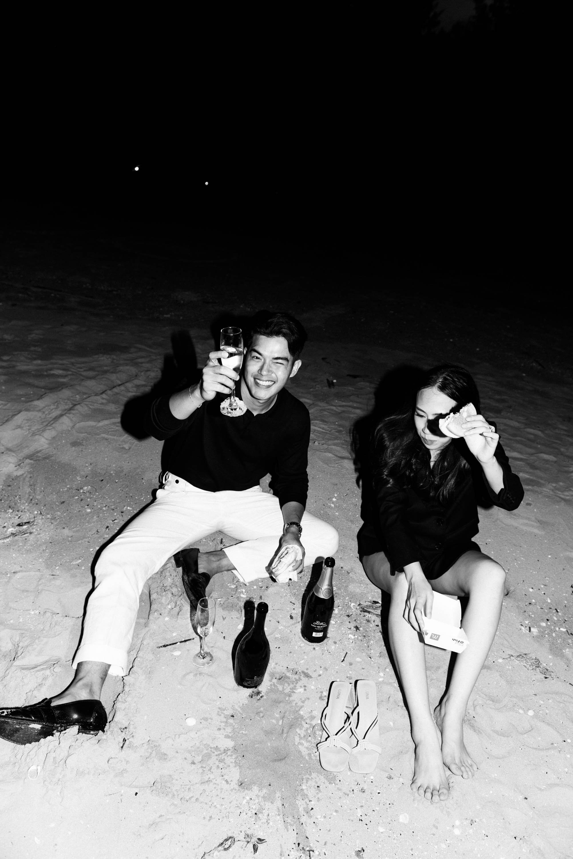 Couple enjoying burgers and champagne together, raising their glasses and a burger in celebration.