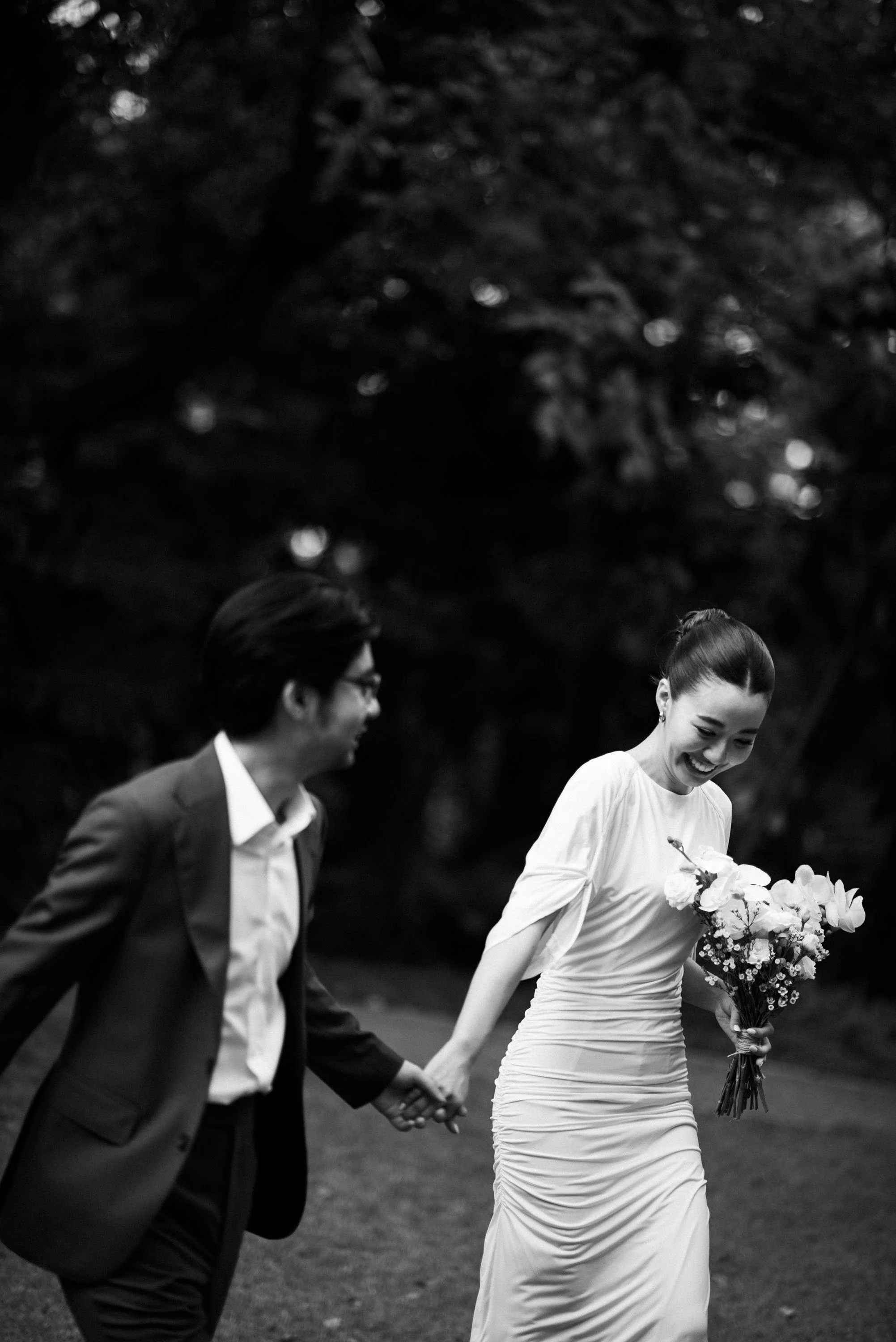 Couple walking hand in hand through the garden as the man looks at his partner.