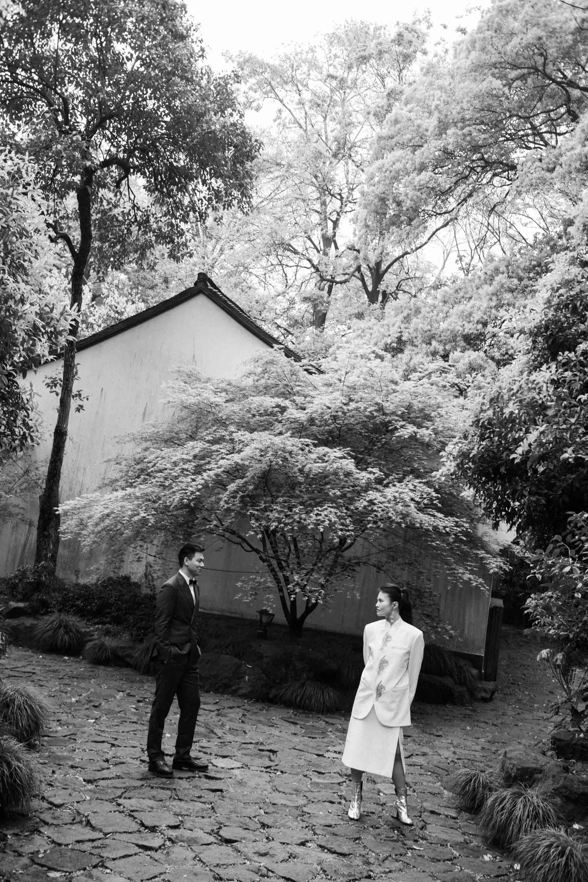 Bride and groom standing beside a historic building in the garden.