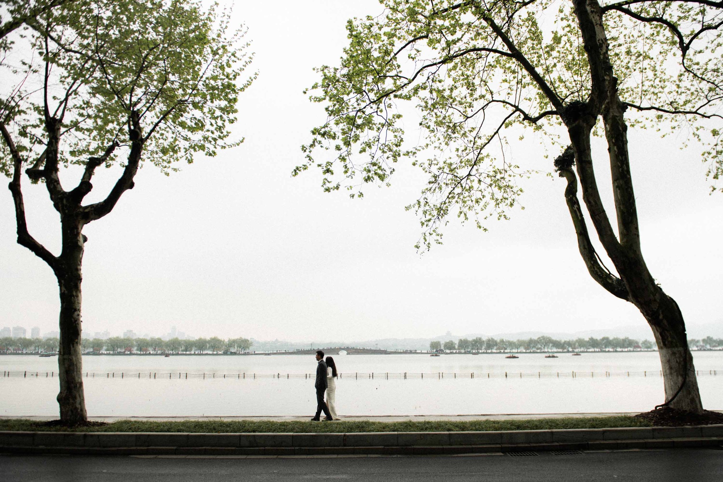 Bride and groom walking beside West Lake.